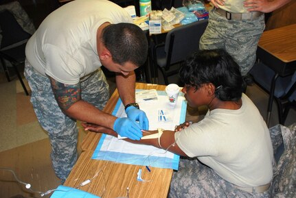 SOTO CANO AIR BASE, Honduras - Army SPC Jose Gonzalez, Joint Task Force-Bravo Joint Security Forces, practices placing an intraveneous saline lock on SSG Annette Baily, JTF-B Medical Operations, during Combat Lifesaver training, here, Dec. 15.  CLS training address proper techniques and procedures to take care of injured Soldiers, which will allow first responders to ensure maximum survivability on the battlefield. (U.S. Air Force photo/Army PFC Kelvin Rivera)