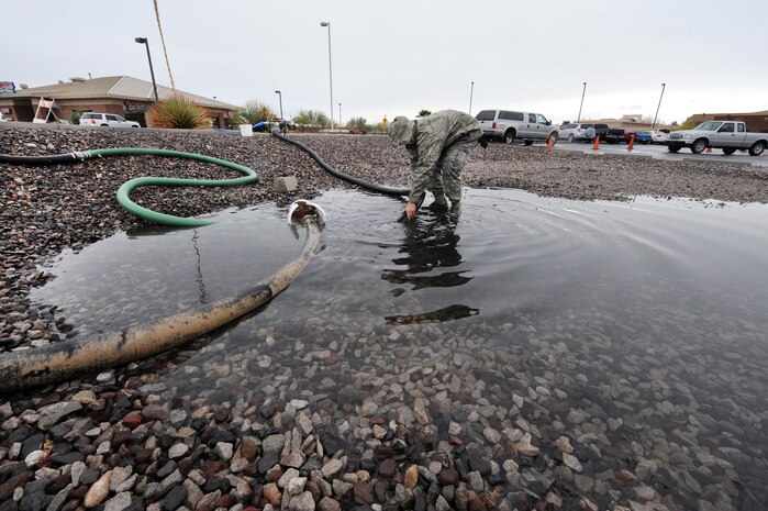 NELLIS AIR FORCE BASE, Nev.--   Senior Airman Brandon Trinkle, 99th Civil Engineer Squadron heavy equipment operator, pumps water out of a ditch near the Commissary parking lot Dec. 22. A heavy winter rainstorm slammed Southern Nevada the fourth week of December. More than an inch of rain was recorded at Nellis over the week. The base populace is reminded when a flash-flood warning is issued that flooding is imminent or occurring. Those living in the affected areas should move to safety immediately. (U.S. Air Force photo by Lawrence Crespo/Released)