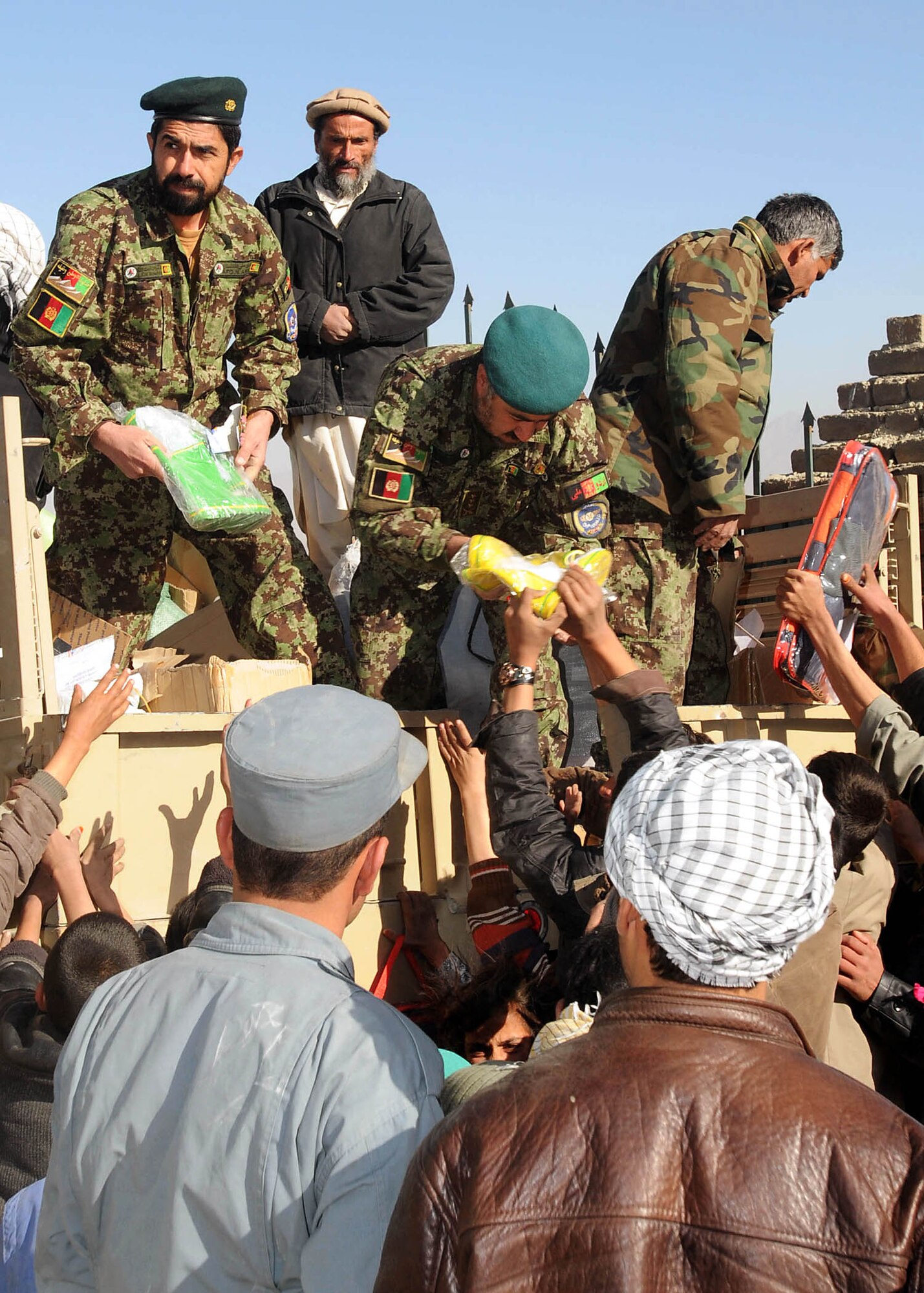 Members of the Afghan air force distribute supplies to children and their families Dec. 22, 2010, in a village north of Kabul. (U.S. Navy photo/Petty Officer 3rd Class Jared Walker)