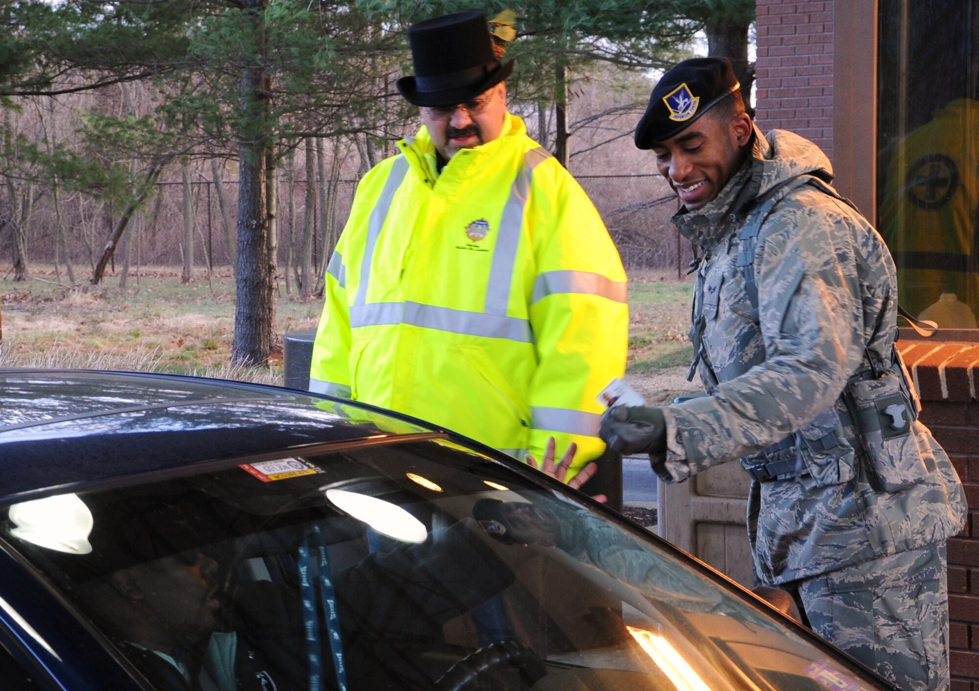 JOINT BASE MCGUIRE-DIX-LAKEHURST -- Diego Villalba greets Joint Base McGuire-Dix-Lakehurst community members while Airman 1st Class Ronald Manotas-Yepes, 87th Security Forces Squadron, checks ID cards Dec. 23 at the Wrightstown Gate. The base’s senior leaders, along with gate entry personnel, check ID cards at the gate and wish all members a safe and happy holidays. Villalba is a member of the 87th Air Base Wing Safety office. (U.S Air Force photo/Airman 1st Class Dennis L. Sloan)