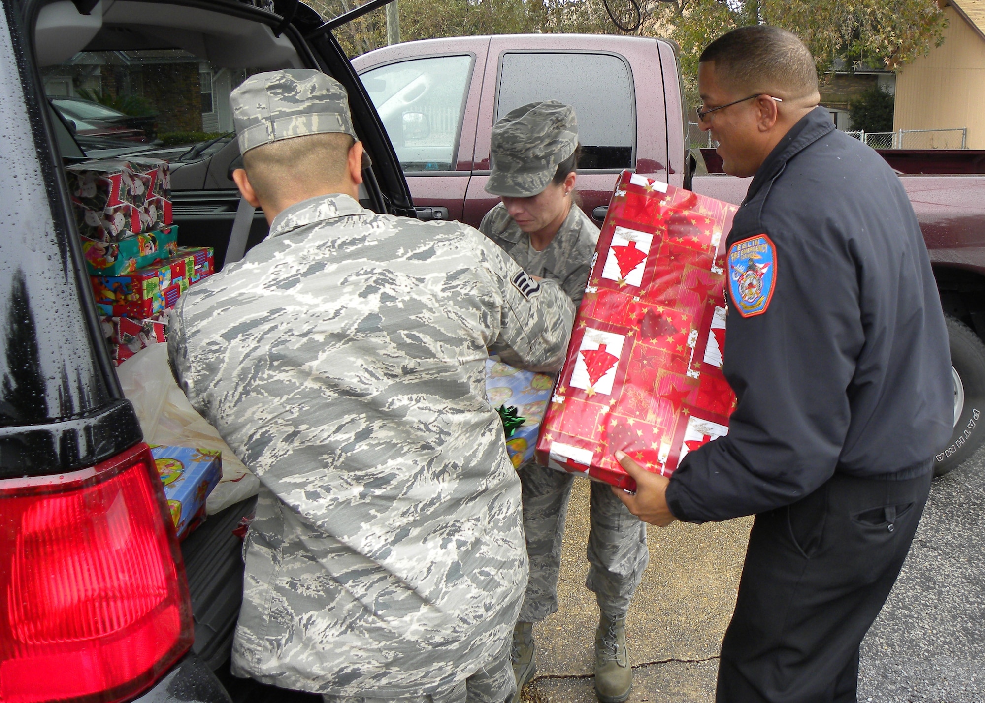 Eglin firefighters unload an SUV full of presents in the driveway of a family they "adopted" from Bruner Middle School, Fort Walton Beach, Fla. Master Sgt. Christy Skerrett center, has worked with her career field's professional organization for 10 years providing Christmas gifts to needy family. It has become an Eglin Fire and Emergency Services annual tradition to gather each other's resources and provide for a family during the holidays. (Courtesy photo)