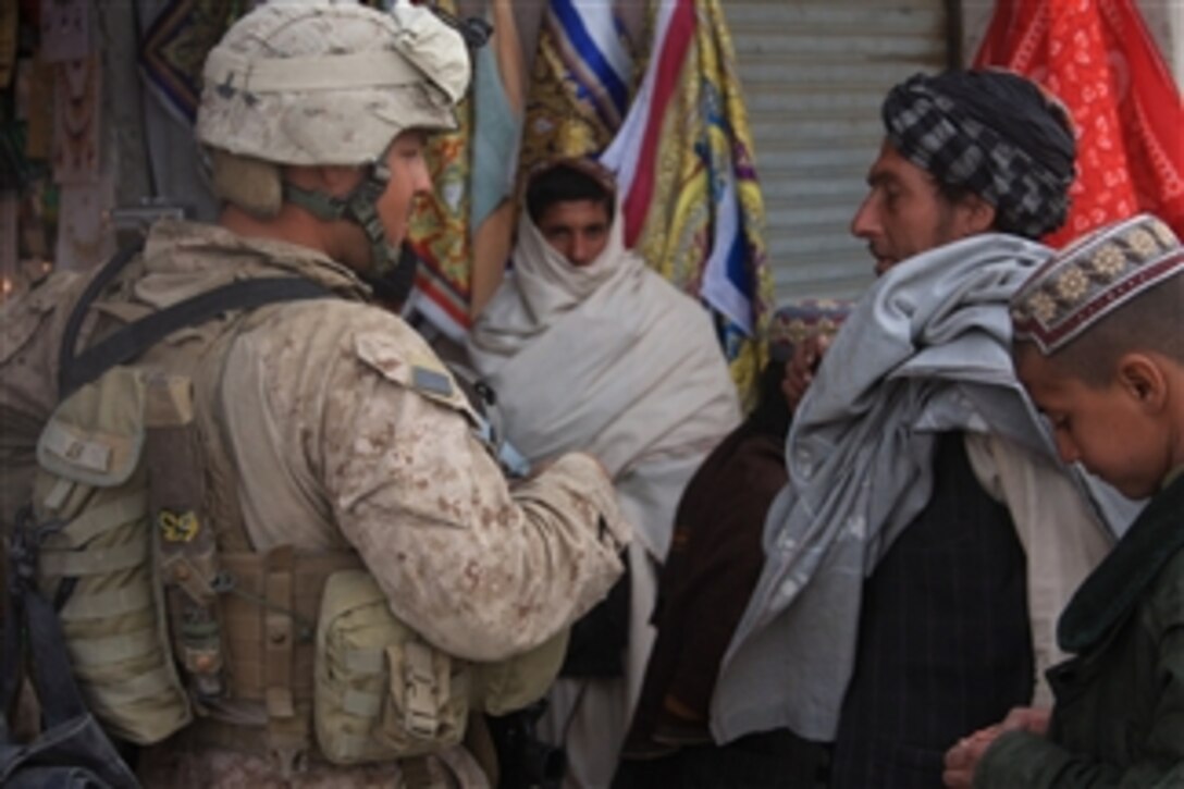 U.S. Navy Petty Officer 3rd Class Raul R. Silva, (left), with Police Mentor Team 1, Headquarters and Service Company, 3rd Battalion, 5th Marine Regiment, talks to Afghan men during a security patrol through a bazaar in Sangin district, Helmand province, Afghanistan, on Dec. 14, 2010.  The Marines conducted security patrols in partnership with the International Security Assistance Force to decrease insurgent activity and gain the trust of the Afghan people.  