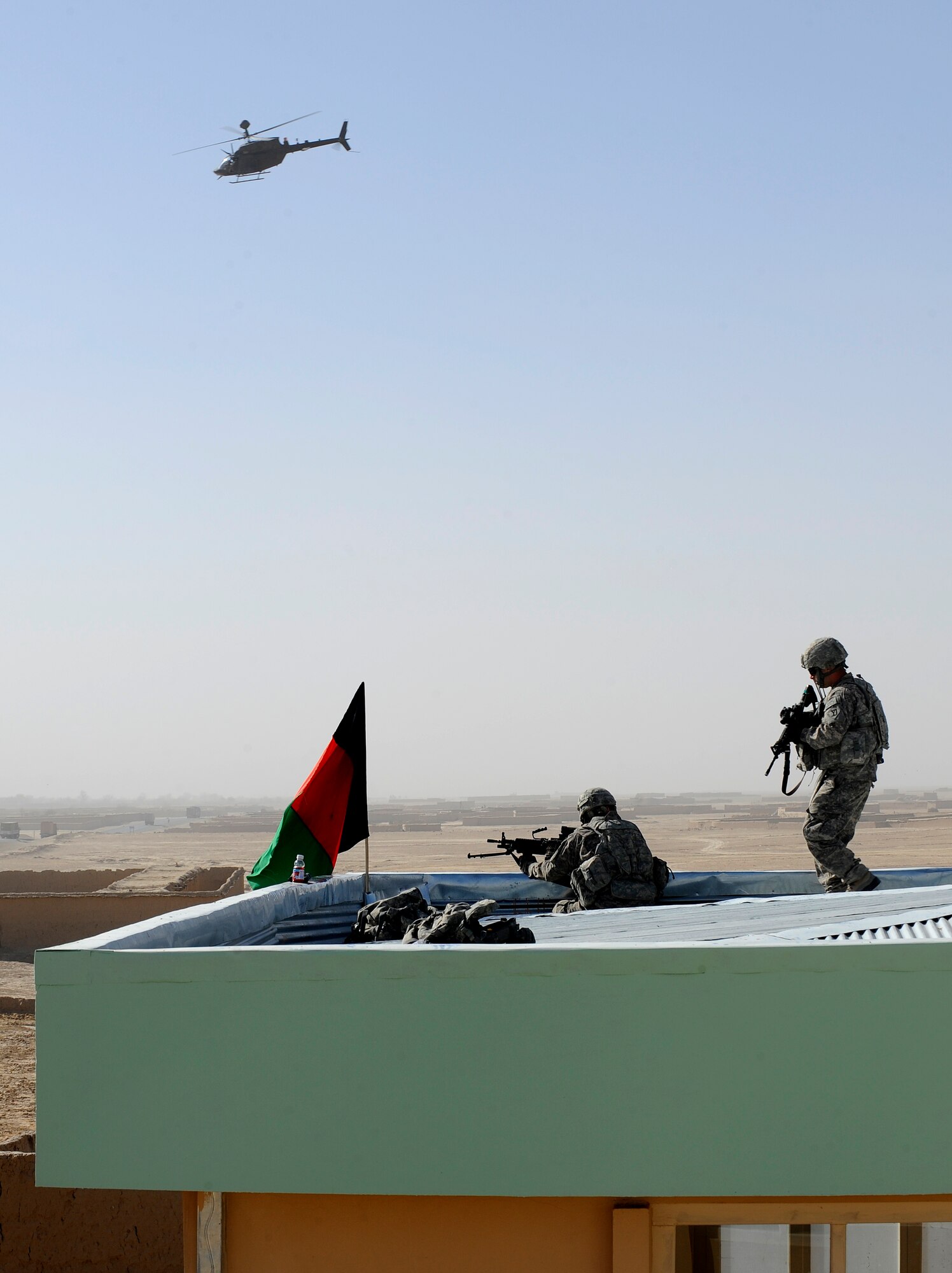 Pvt. 1st Class Benjamin Frade, left, and Sgt. Eric Diluzio provide overwatch from the roof of the new Shajoy District Center during the center's opening ceremonies, Dec. 23. Provincial leaders were on hand to open the district center and speak to the more than 90 local villagers in attendance. Pvt. Frade and Sgt. Diluzio are assigned to Provincial Reconstruction Team Zabul's security force. (U.S. Air Force photo/Staff Sgt. Brian Ferguson) (Released).