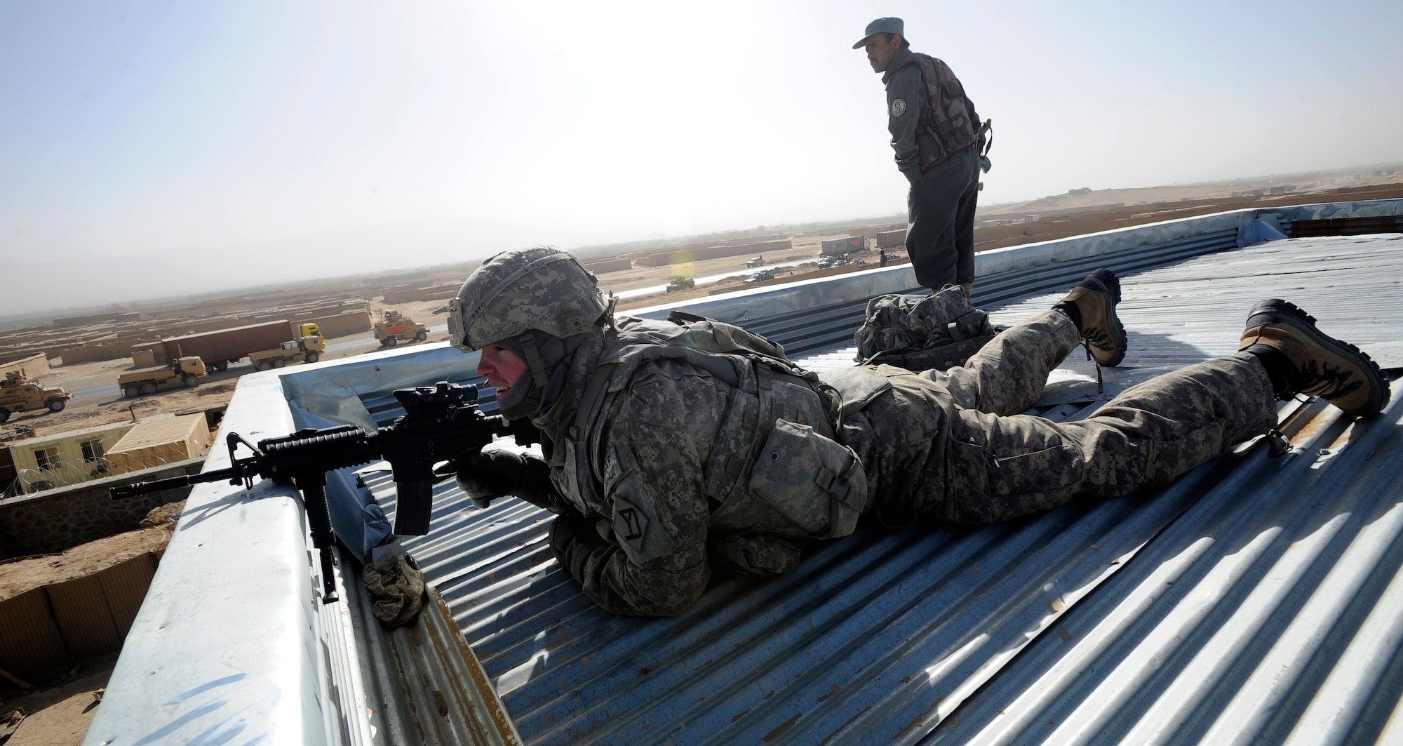 Pvt. 1st Class Terence Mayo and an Afghan National Police officer provide overwatch from the roof of the new Shajoy District Center during the center's opening ceremonies, Dec. 23. Provincial leaders were on hand to open the district center and speak to the more than 90 local villagers in attendance. Pvt. Mayo is assigned to Provincial Reconstruction Team Zabul's security force. (U.S. Air Force photo/Staff Sgt. Brian Ferguson) (Released).