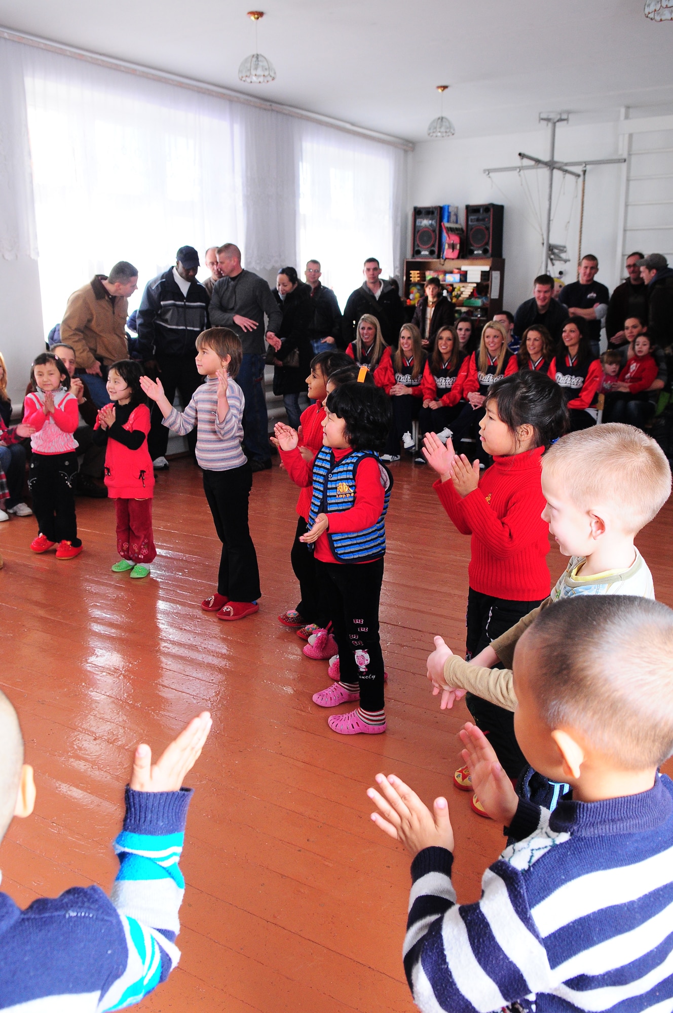 TRANSIT CENTER AT MANAS, Kyrgyzstan - Children from a local school perform for the New England Patriot Cheerleaders during their visit as part of an Armed Forces Entertainment tour Dec. 23.  The cheerleaders took a cultural tour of Bishkek, performed for deployed military members and toured the Transit Center at Manas. (U.S. Air Force photo/Staff Sgt. Stacy Moless)