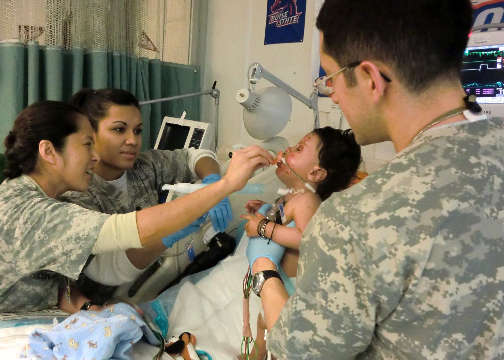 Capt. Mernamie Cunamay (left) distracts a patient with a pacifier while Staff Sgt. Shellsea Quiroz (center) and Capt. Eric Tovar (right) administer chest physiotherapy to an Afghan infant.  The 455th Medical Group Airmen provided the therapy to loosen secretion in the lungs for the child who suffered burns from a stove explosion.  (U.S. Air Force Photo/Capt. Erick Saks)