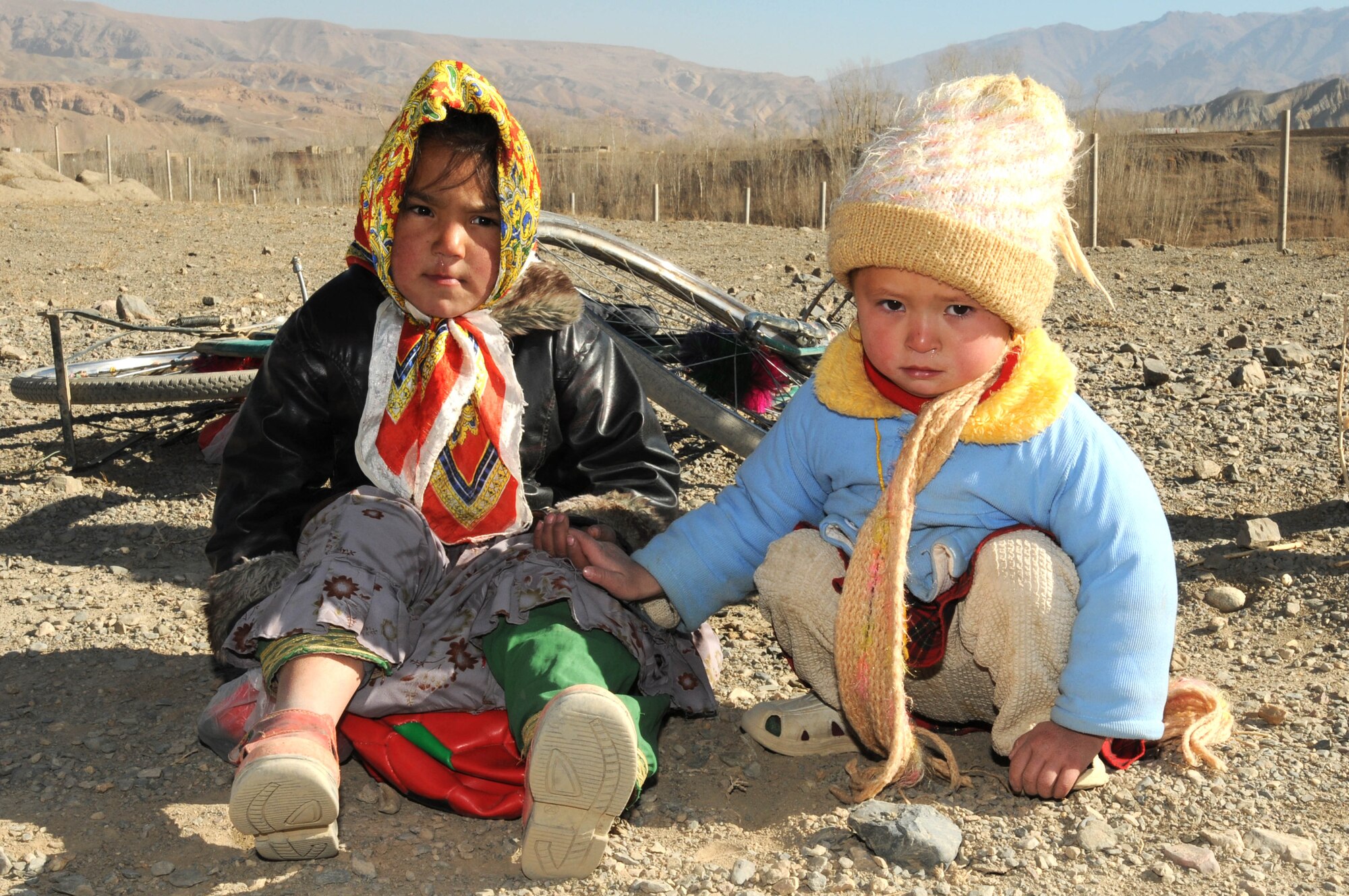 BAMIYAN, Afghanistan -- Two children sit on top of soccer balls and Jolly Ranchers they received from Afghan Air Force and NATO Air Training Command-Afghanistan troops as part of a humanitarian assistance mission in the province. (U.S. Navy photo by Mass Communications Specialist 2nd Class Vladimir Potapenko/RELEASED)