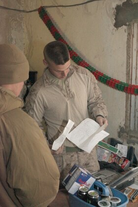 Sgt. Alan L. Lewis, Marine Corps Community Services specialist, Headquarters and Service Company, 1st Marine Logistics Group (Forward), checks the special order list while operating the mobile post exchange near the Kajaki Dam, Dec. 25. The MCCS Marines arrived in Kajaki on Christmas day to provide goods such as snacks and other comfort items to the Marines in the area.