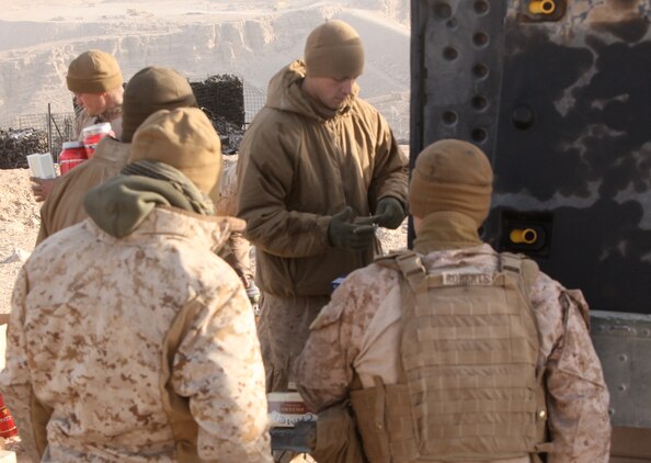 Sgt. Alan L. Lewis, Marine Corps Community Services specialist, Headquarters and Service Company, 1st Marine Logistics Group (Forward), cashes out Marines from Bravo Battery, 1st Battalion, 10th Marine Regiment, 1st Marine Division (Forward), atop Observation Post Athens near the Kajaki Dam, Dec. 26. Marines with 1st MLG (FWD) arrived in Kajaki on Christmas day to provide goods such as snacks and other comfort items to the Marines in the area.