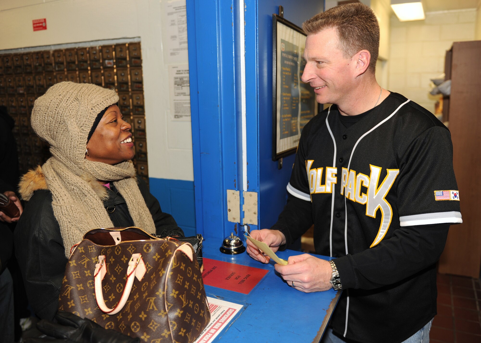 KUNSAN AIR BASE, Republic of Korea -- Col. John Dolan, 8th Fighter Wing commander, speaks with Master Sgt. Claudette Hutchinson, 8th Fighter Wing public affairs superintendent, at the parcel pickup window here Dec. 24, 2010. Colonel Dolan and his family volunteered at the post to help with package sorting and distribution. (U.S. Air Force photo/Senior Airman Ciara Wymbs) 