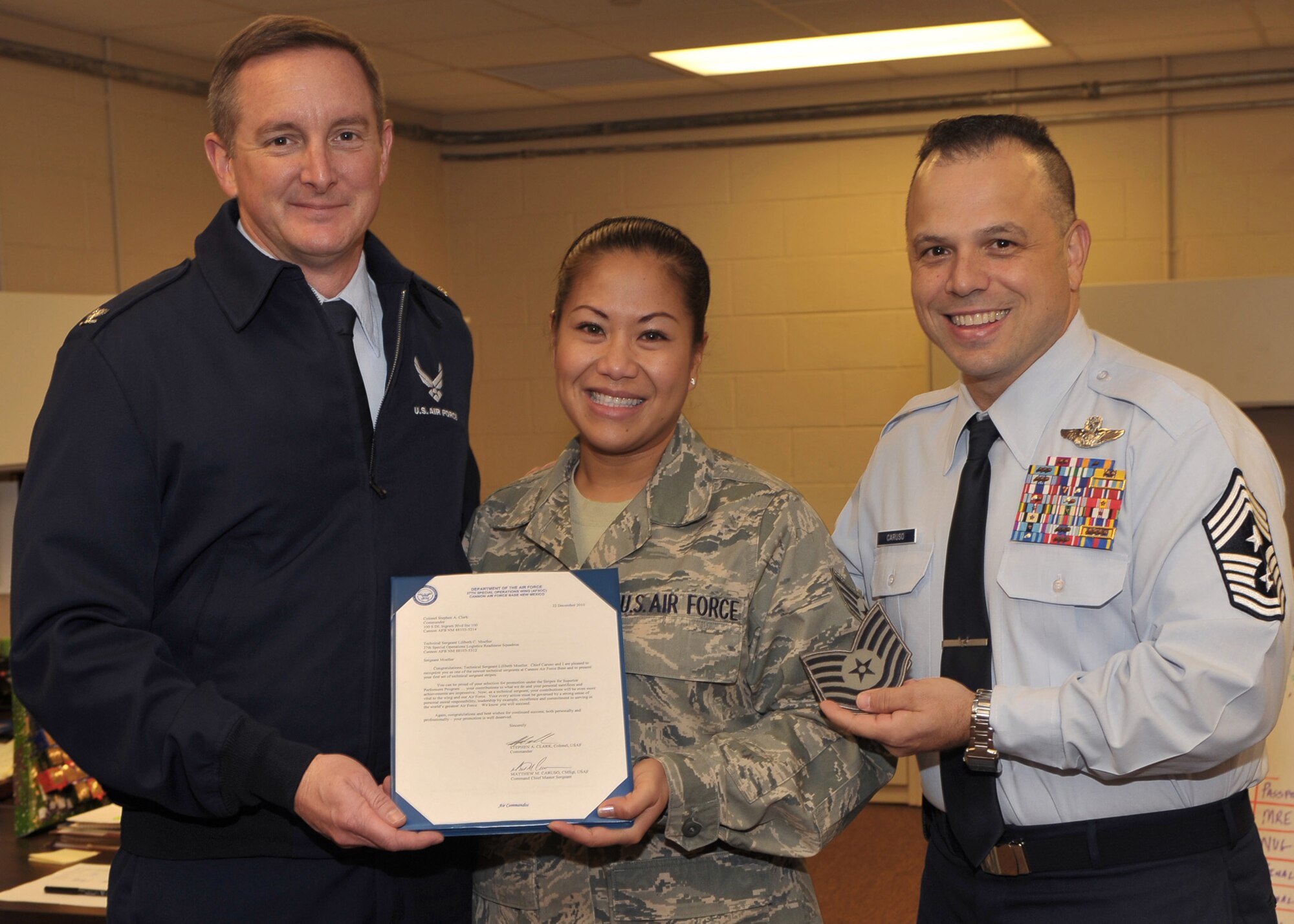 Col. Stephen Clark, 27th Special Operations Wing commander, along with Chief Master Sgt. Matthew Caruso. 27th Special Operations Wing command chief,  present Staff Sgt. Lilibeth Moeller, 27th Special Operations Logistics Readiness Squadron, with an unexpoected STEP, or Stripes for Exceptional performers, promotion to technical sergeant, Dec. 27, at Cannon Air Force Base, N.M. (U.S. Air Force photo by Senior Airman James Bell)