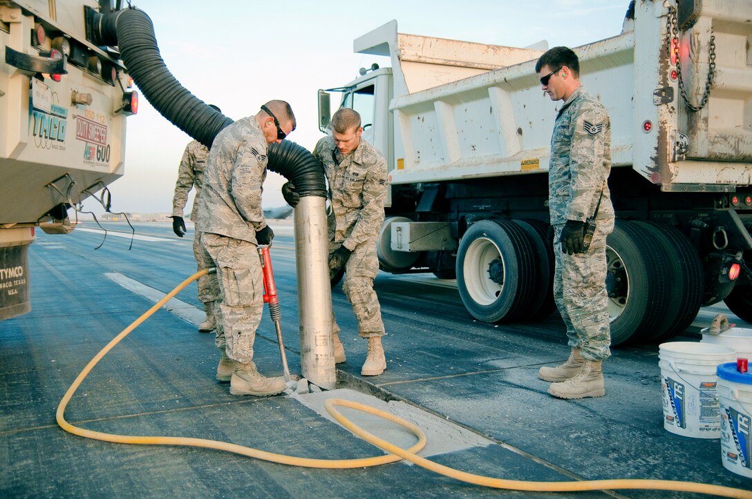 Members of the 386th Expeditionary Civil Engineer Squadron's runway repair team excavate cracked pavement and remove debris with a sweeper truck Dec. 10, 2010, on a runway at an air base in Southwest Asia. The team makes weekly repairs to the runways here. (U.S. Air Force photo/Maj. Dale Greer)