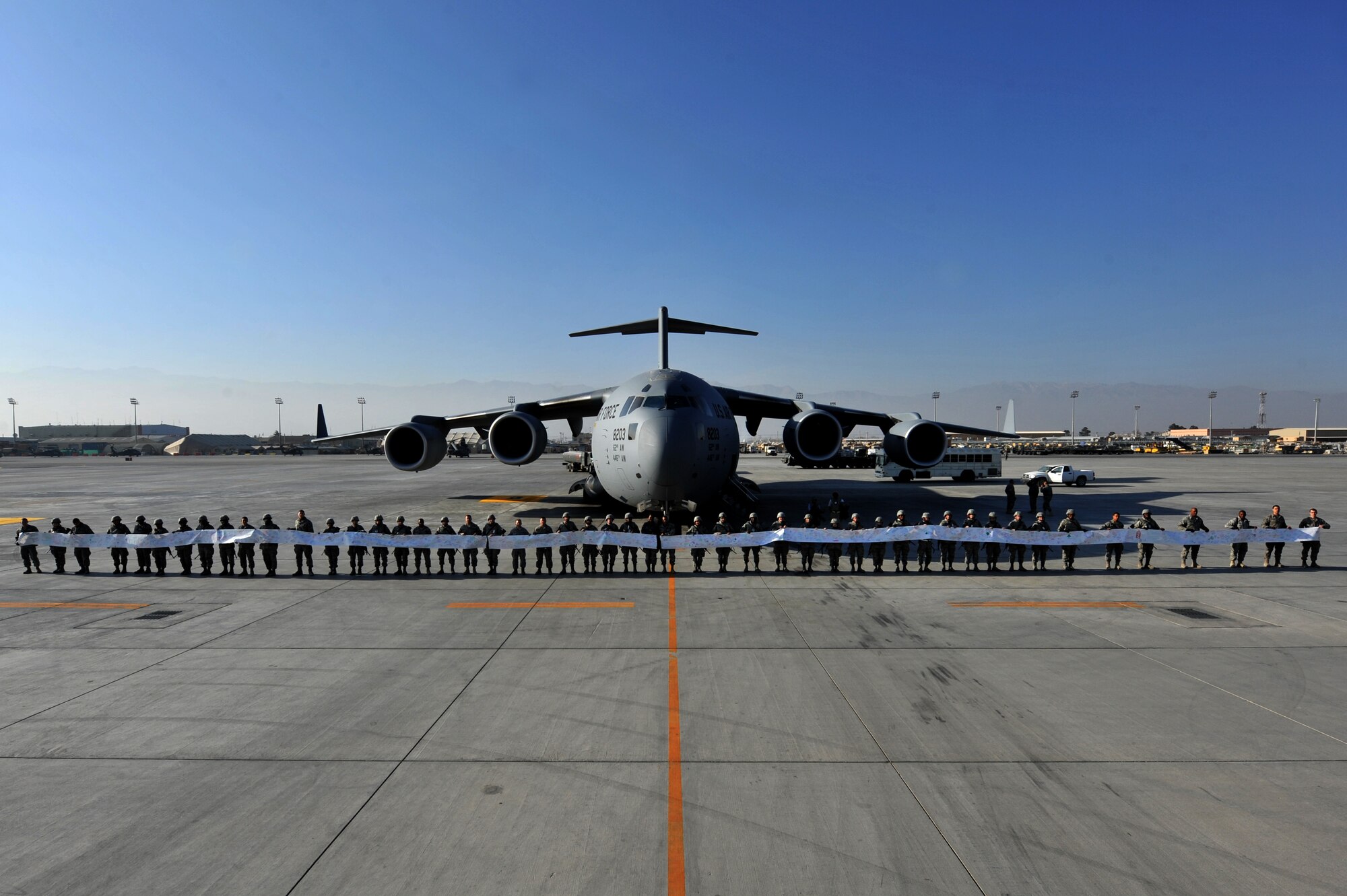 Airmen from the 455th Air Expeditionary Wing display part of a holiday scroll in front of a C-17 Globemaster III at Bagram Airfield on Christmas Eve.  The several hundred foot scroll was sent by George and Shirley Jackson of American Corner, Md.  The Jackson family began collecting holiday messages for Airmen in the spring to ensure the scroll would arrive in time for the holidays.  (U.S. Air Force photo/Senior Airman Sheila deVera)