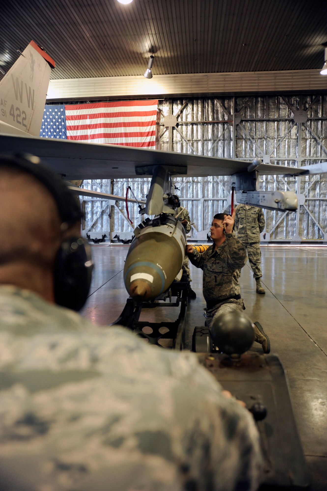 U.S. Air Force Staff Sgt. Nikolai Yeakel (right), 35th Maintenance Squadron weapons load crew chief, directs Airman 1st Class Cassey Dukart, 35th MXS weapons load crew member, as they compete in the final round of the 35th Fighter Wing load crew competition at Hangar 911, Misawa Air Base, Japan; Dec. 17, 2010. Sergeant Yeakel helped align the munitions with the F-16 Fighting Falcon's bomb rack. (U.S. Air Force photo by Tech. Sgt. Russell McBride/Released)