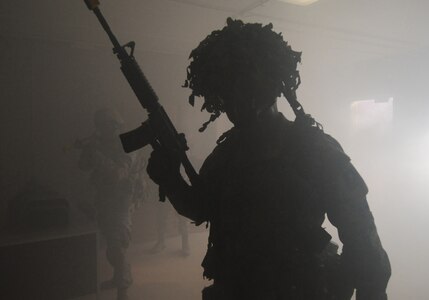 A training instructor enters a smoke-filled room at Camp Bullis, Texas, in search of enemy combatants during a training demonstration Oct. 20. Air Education and Training Command commanders participated in the training exercise to witness training capabilities first-hand. (U.S. Air Force photo/David Terry)