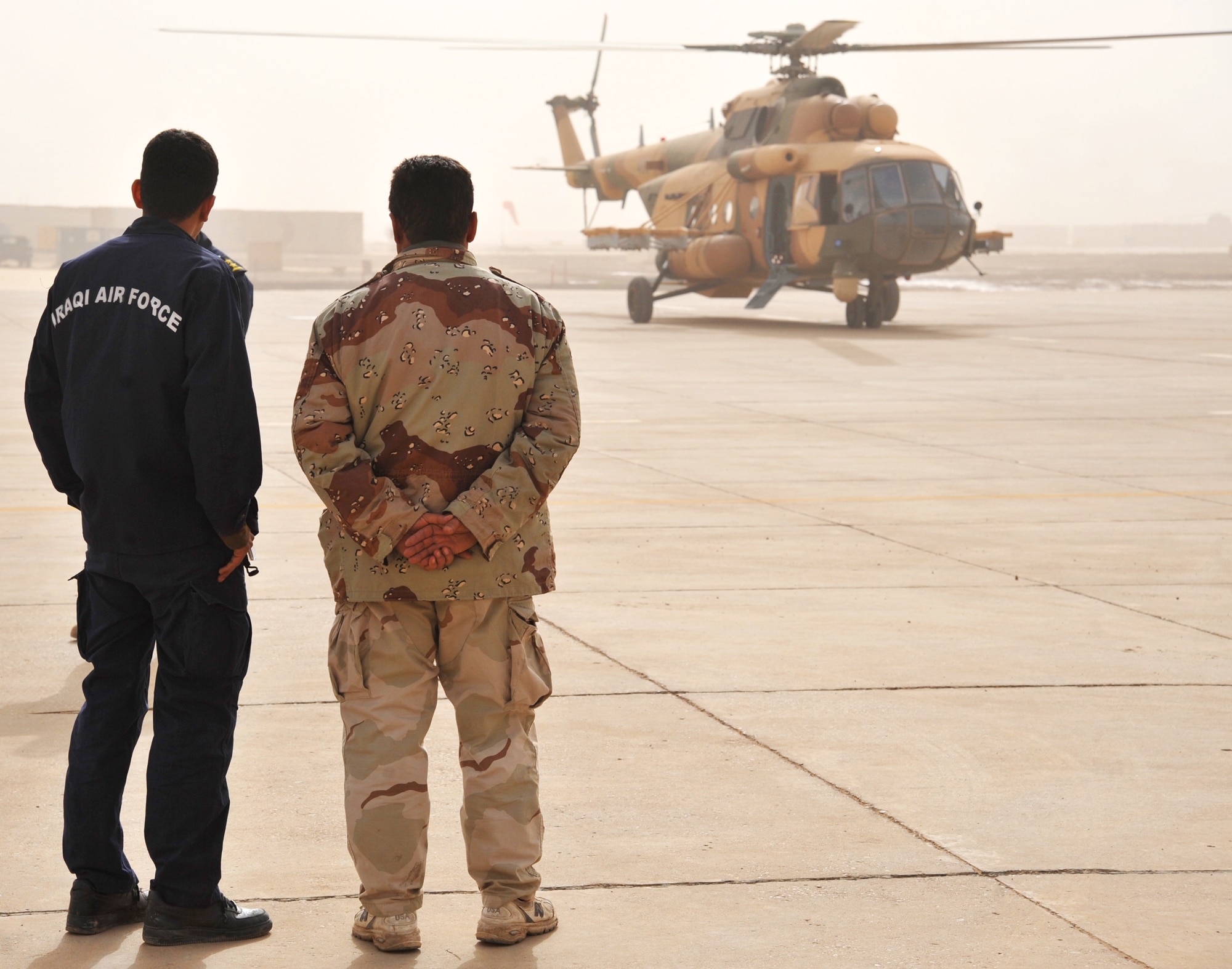 Two Iraqi Army Aviation Command soldiers observe a Mi-17 helicopter as it prepares to take off Dec. 15, 2010, in Taji, Iraq. 721st Air Expeditionary Advisory Squadron air advisors work with the AAC at Taji to advise and assist them in building a safe, self-sustaining Iraqi rotary-wing force. (U.S. Air Force photo/Senior Airman Andrew Lee)