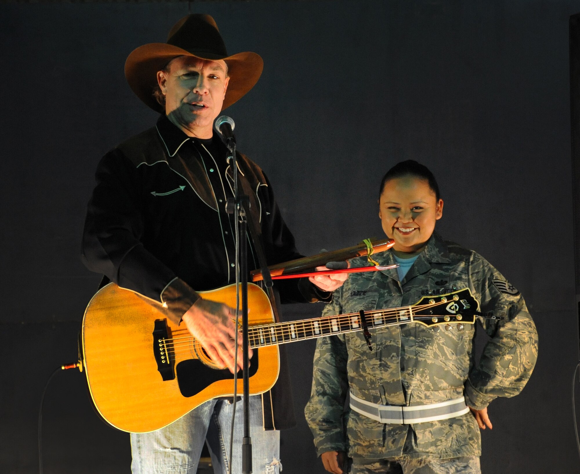SOUTHWEST ASIA -- Country singer Michael Peterson gives a flute to Staff Sgt. Leander Yazzie, 386th Expeditionary Force Support Squadron, as a gift for her role in the organization of this event for the base. (U.S. Air Force photo by Senior Airman Cynthia Spalding)