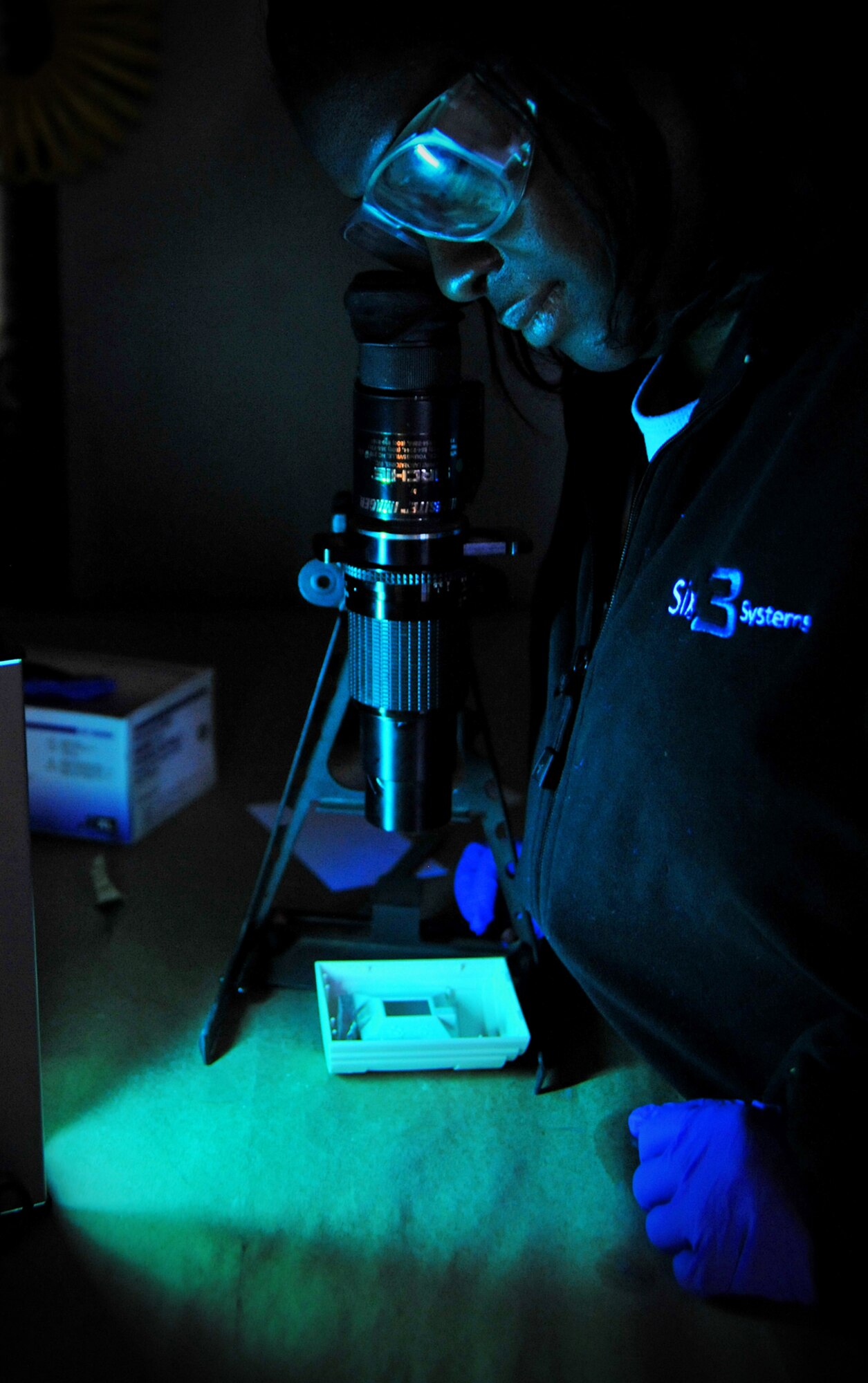 Nicola Charles, United States Forces-Iraq Combined Joint Task Force Troy’s Combined Explosives Exploitation Cell latent print examiner, takes a look through a Reflective Ultraviolet Imaging System fingerprint scope to look for a fingerprint using an ultraviolet light source Dec. 8, 2010, on Camp Victory, Iraq. One key responsibility of CJTF Troy and CEXC is neutralizing the improvised explosive devices’ threat through collection and exploitation of IED evidence and related intelligence. CJTF Troy is dedicated to countering IEDs and saving lives of Iraqi and joint forces conducting Operation New Dawn. (U.S. Air Force photo by Senior Airman Andrew Lee)