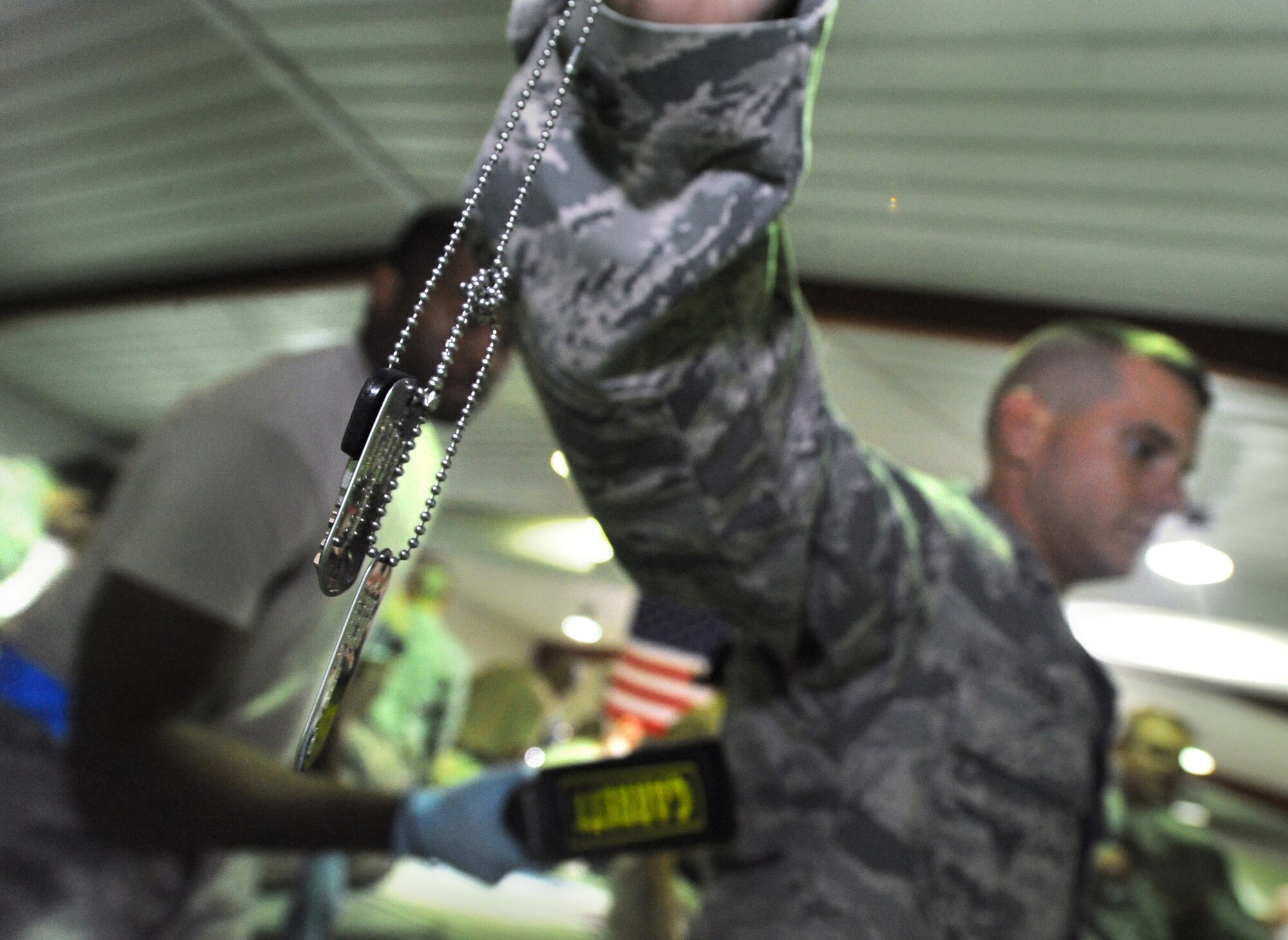 SOUTHWEST ASIA -- An Airmen holds his dog tags out while being searched during the customs process Dec. 21. The 386th Air Expeditionary Wing was able to cut down the redeployment process with the implementation of an all-Air Force customs process, with occasional Navy augmentees, a first in the Air Force Central Command area of responsibility. (U.S. Air Force photo by Senior Airman Cynthia Spalding)