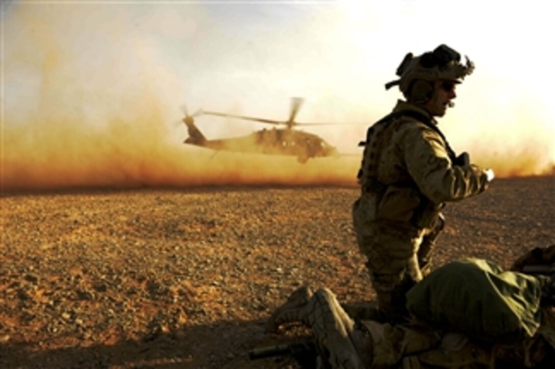 U.S. Air Force Capt. Nick Morgans, with the 46th Expeditionary Rescue Squadron, protects a simulated casualty as an HH-60 Pave Hawk helicopter takes off during a mass casualty exercise near Kandahar, Afghanistan, on Dec. 24, 2010.  