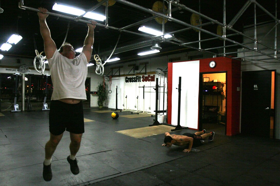 Dr. Charles Farwell, a physician with Navy healthcare, executes pull-ups while Jesse Lujan, a local biochemist, performs push-ups at CrossFit SoCal in Mira Mesa, Calif., Dec. 28. The cross-fitters spent 20 minutes doing as many pull-ups, push-ups and squats as possible for their daily workout.