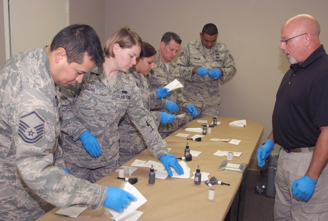 An instructor with Six3 Systems Inc. helps 4th Combat Camera Airmen as they practice fingerprinting techniques during a battlefield forensics course at March Air Reserve Base, Calif. (U.S. Air Force photo/Tech. Sgt. Joseph Zuccaro)
