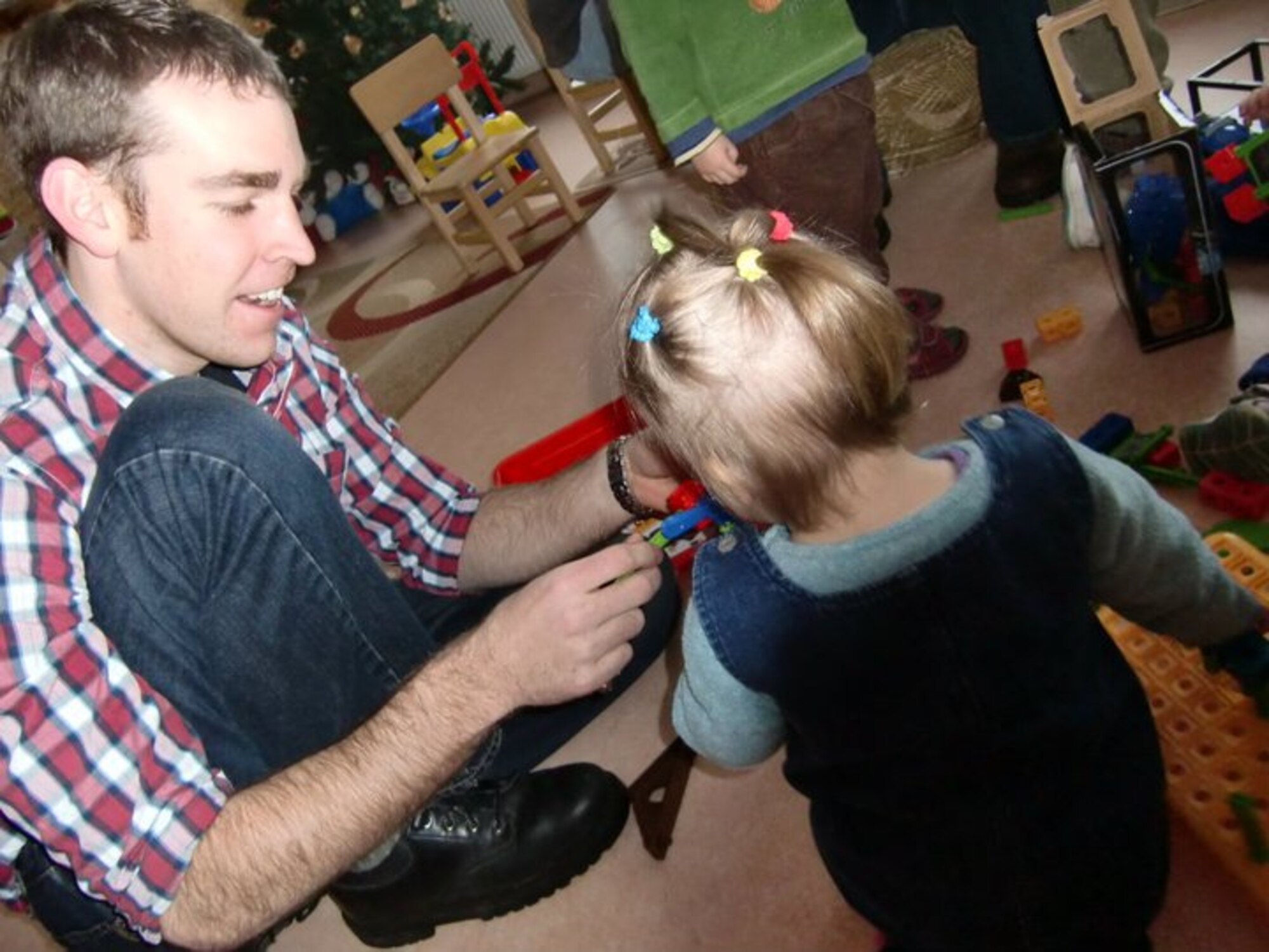 SIAULIAI, Lithuania – 2nd Lt. Tyler Stubbs, 493rd Expeditionary Fighter Squadron Officer-in-Charge of Communications, hands a toy to a young girl at Kusenai Orphanage Dec. 25. More than 20 Airmen from the 493rd EFS came bearing approximately 200 gifts for the children to open on Christmas Day. Lieutenant Stubbs is deployed from the 1st Combat Communications Squadron at Ramstein Air Base, Germany. (U.S. Air Force photo/Lauren Stubbs) 