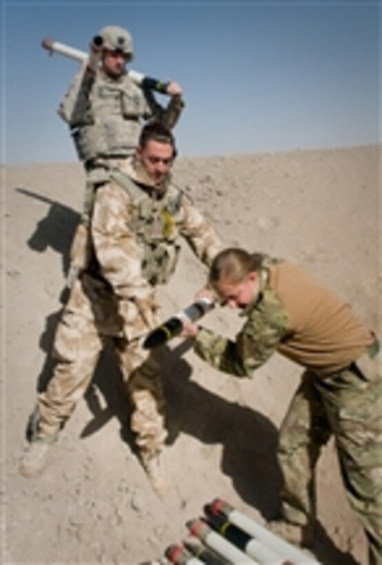A U.S. Army soldier (top) and British service members place unserviceable rockets into a pit before destroying them outside of Kandahar Airfield, Afghanistan, on Dec. 22, 2010.  The rockets were destroyed by an international team of service members to prevent them from falling into Taliban hands or injuring the local populace.  