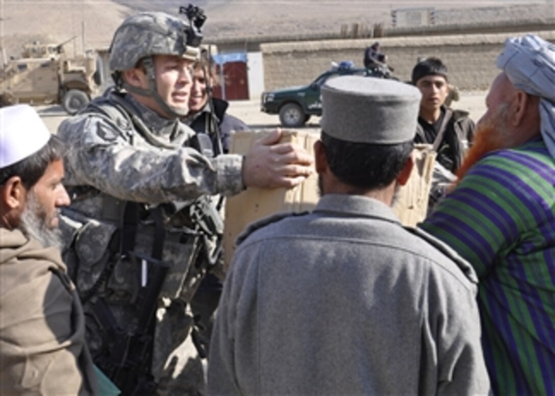 Lt. j.g. Daniel Rhame, operations officer for the Nuristan Provincial Reconstruction Team, gives a box of radios to a teacher at a girl's school on Dec. 27, 2010.  The reconstruction team gave the radios to the teachers as a source of news and information the teachers can then use to keep their students up to date in current events.  