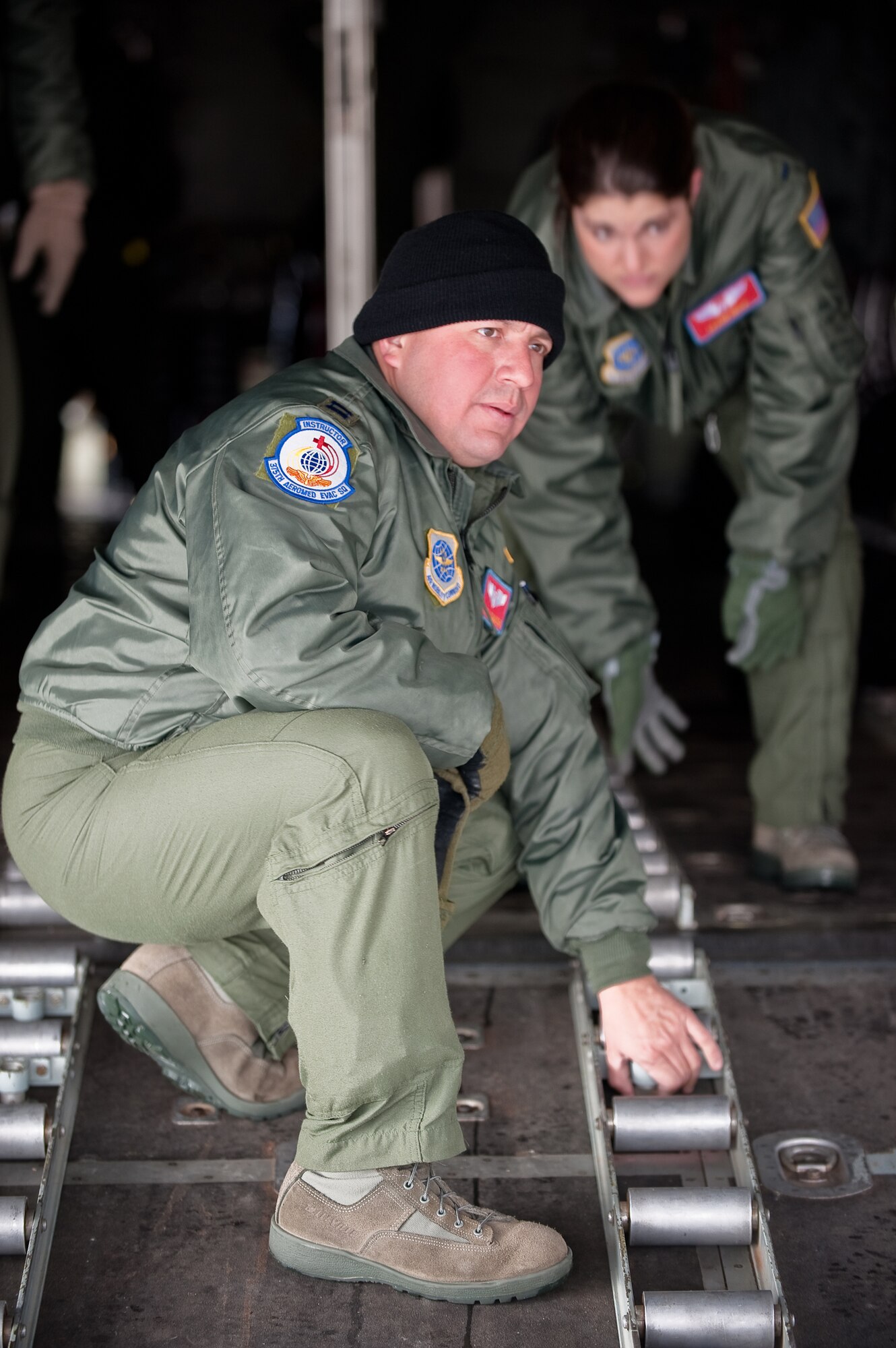 KENTUCKY AIR NATIONAL GUARD BASE, LOUISVILLE, KY. -- Capt. John Camacho, a flight nurse instructor, and 1st Lt. Leann Hisle, second flight nurse, remove a cargo-pallet roller system from the floor of a C-130 on the flight line of the Kentucky Air National Guard Base Feb. 11, 2010. The Airmen, both assigned to the 375th Aeromedical Evacuation Squadron at Scott Air Force Base, Ill., were reconfiguring the aircraft for aeromedical simulations to be conducted over the skies of southern Ohio later in the day as part of a U.S. Air Force Critical Care Air Transport Team training course. Most of the C-130's seating and cargo-handling equipment were removed to make room for patient litters and medical-support gear. (U.S. Air Force by Maj. Dale Greer)