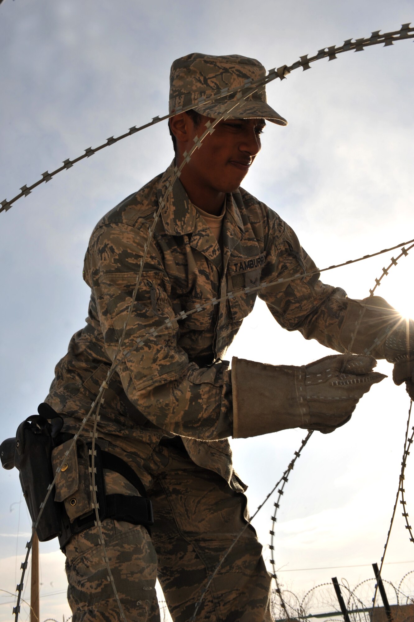 Airman 1st Class Lee Tamburro, 455th Expeditionary Security Forces Squadron, moves concertina wire lay out on the gravel to the walking path pavement, Bagram Airfield, Afghanistan, Dec. 30, 2010. The security forces airman are moving the C-wire from the gravel to a pavement walking path which local national employee use every day. The move of the C-wire is to improve the quality of life for the more than five thousand Bagram local national employees. (Air Force photo/Senior Airman Sheila deVera)