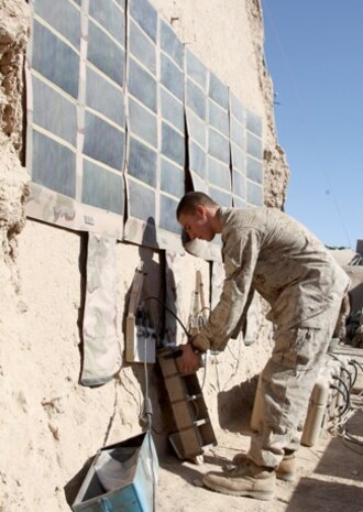 Lance Cpl. Dakota Hicks, a native of Laharpe, Ill., and a machine gunner with 2nd Platoon, India Company, 3rd Battalion, 5th Marine Regiment, connects a radio battery to a Solar Portable Alternative Communication Energy System (SPACES) at Patrol Base Gumbatty in Sangin District, Dec. 31, 2010. SPACES is a flexible solar panel, that can be carried by a Marine and is used for recharging radio batteries. With more room in their packs from fewer batteries, the coalition forces can pack more essentials, like ammunition. SPACES is one of four renewable energy devices that comprise the Experimental Forward Operating Base project.