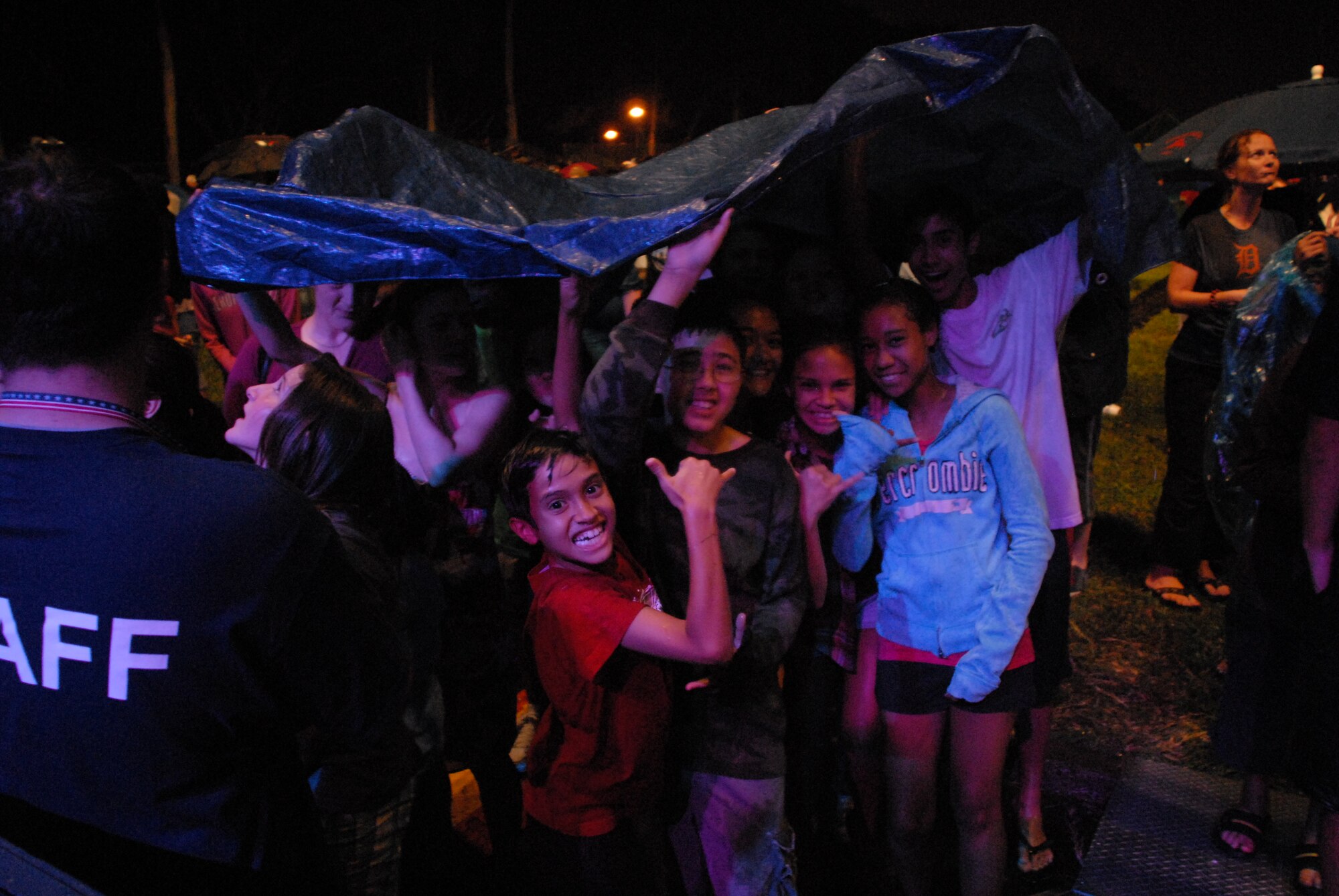 HICKAM AIR FORCE BASE, Hawaii - Kids pull a tarp over their heads to cover up from the rain during a performance by the Lt. Dan Band here, Jan 30. The Lt. Dan Band performed songs from Bruce Springsteen, Linkin Park, to Aretha Franklin and Jimmy Hendrix. The Lt. Dan Band performs 30-40 shows per year, most of which are in support of the USO and other charities or benefits. (U.S. Air Force photo by Senior Airman Gustavo Gonzalez)