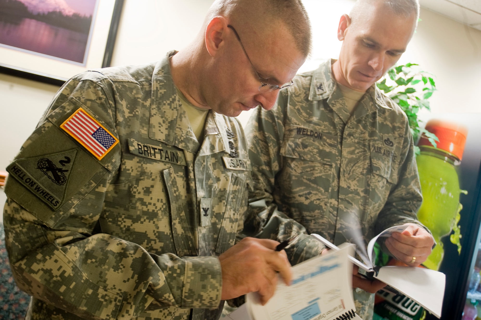 Col. Thomas H. Brittain, Joint Base Lewis-McChord commander and Col. Kenny Weldon, JBLM deputy commander, review notes prior to conducting a briefing for McChord Field civilians and servicemembers at the base theater Monday. (U.S. Air Force Photo/Abner Guzman)