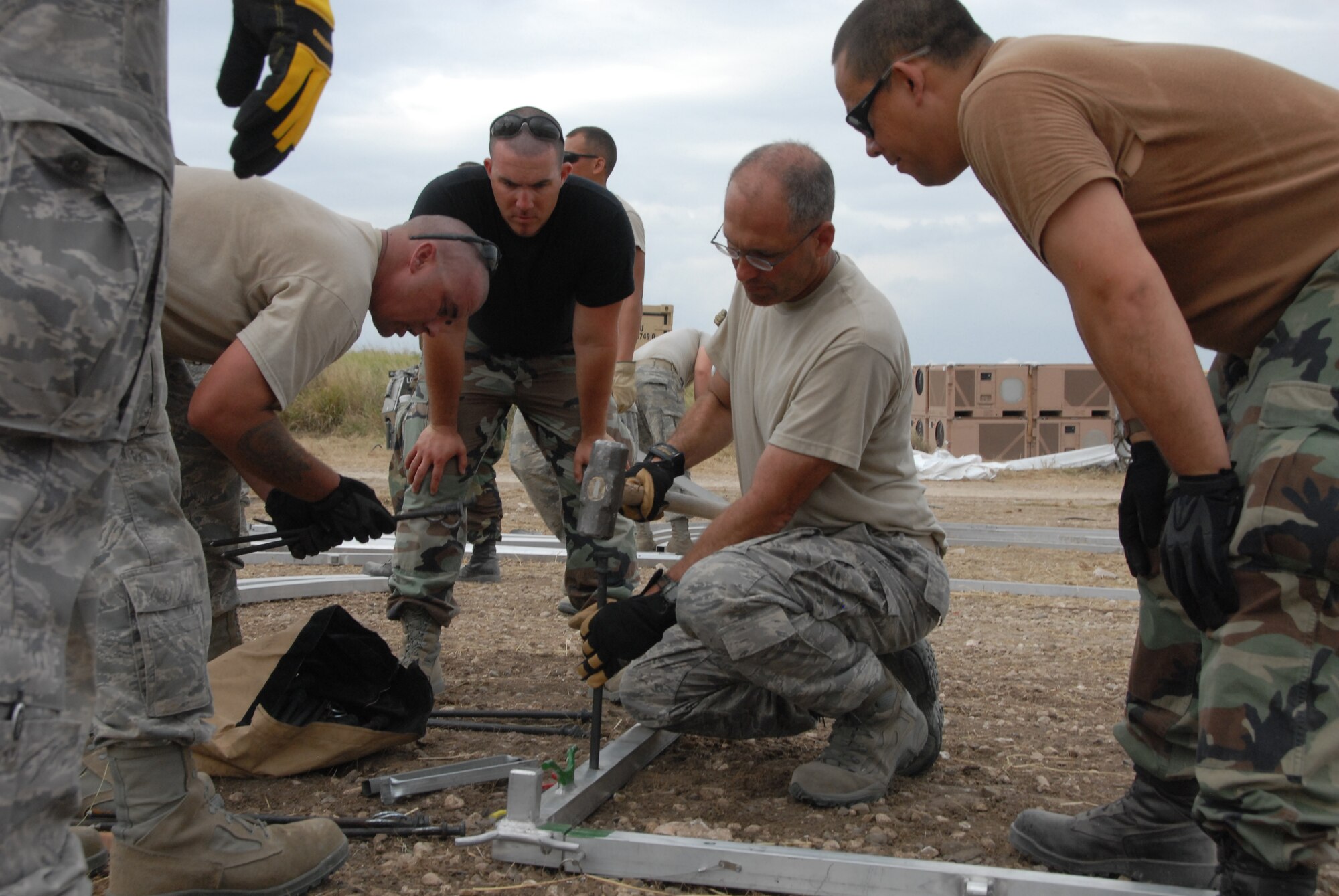 Lt. Col. Mark Green (center), commander of the 190th Civil Engineering Squadron deployed to Haiti, demonstrates the proper technique for anchoring an Expeditionary Medical Support (EMEDS) hospital.  Green, who commanded the Guardsmen that built the EMEDS in Greensburg, Kansas, in 2007, is one of 46 Kansas Guardsmen deployed to build infrastructure for sustained operations in Haiti.