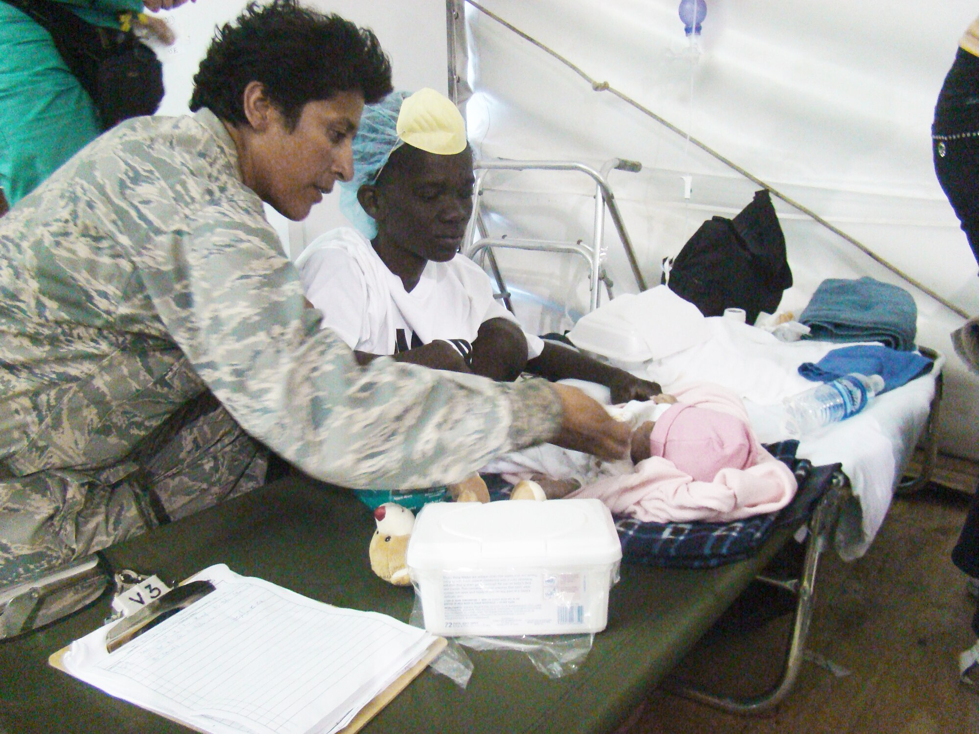 Chaplain (Capt.) Eusebia Rios blesses one of three triplets in the children's ward of a hospital compound adjacent to the Toussaint L'Ouverture International Airport in Port-au-Prince, Haiti, Jan. 29, 2010. The babies were born in the wake of the 7.1 magnitude earthquake which devastated the capital city Jan.12. Chaplain Rios, deployed from the 27th Special Operations Wing at Cannon Air Force Base, N.M., serves as the only chaplain to more than 1,500 military men and women encamped at the airport as part of Operation Unified Response. Known as the "Happy Chappy," Chaplain Rios ranges the airport day and night ministering to the needs of military and civilian alike, lifting their spirits and raising morale with each "Amen" she offers. (U.S. Air Force photo/Chief Master Sgt. Ty Foster)              