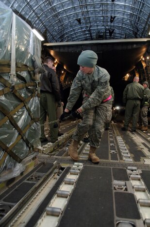 Staff Sgt. Whitney Armstrong chains down cargo on a McChord AFB, Wash., C-17 in Toledo, Ohio, Jan. 30. The C-17 from McChord AFB took off from Charleston AFB to pick up cargo in Ohio before departing to Port-au-Prince, Haiti. Pallets and cargo must be precisely aligned along floor rollers in order to perform a smooth transfer of cargo onto the aircraft. Sergeant Armstrong is a loadmaster with the 179th Logistics Readiness Squadron. (U.S. Air Force Photo/Airman 1st Class Lauren Main)