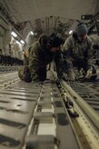 Airmen from the 179th Logistics Readiness Squadron attach chains to the cargo floor of a McChord AFB, Wash., C-17 aircraft to prevent the cargo from shifting during flight in Toledo, Ohio, Jan. 30. The cargo included numerous pallets of supplies, two mobile lighting stations and was later transported to Port-au-Prince, Haiti, in support of Operation Unified Response. (U.S. Air Force Photo/Airman 1st Class Lauren Main)