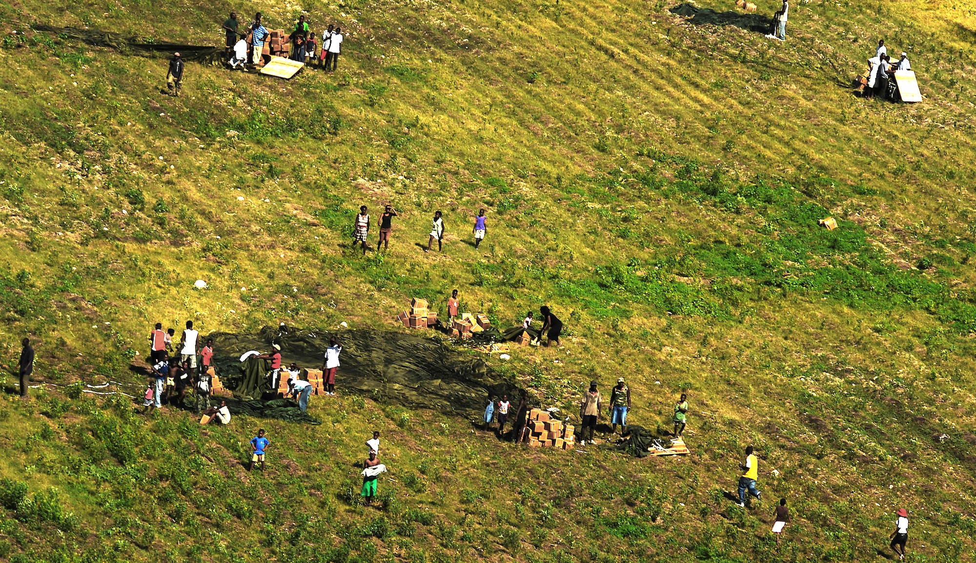 Haitians collect bottles of water and rations of food air delivered by a Charleston AFB C-17 Globemaster III aircraft Jan. 23, 2010, in the outlying area of Port-au-Prince, Haiti. The mission was flown as part of Operation Unified Response to save lives and bring relief to suffering people in Haiti. (U.S. Air Force photo by Tech. Sgt. James L. Harper Jr./Released)