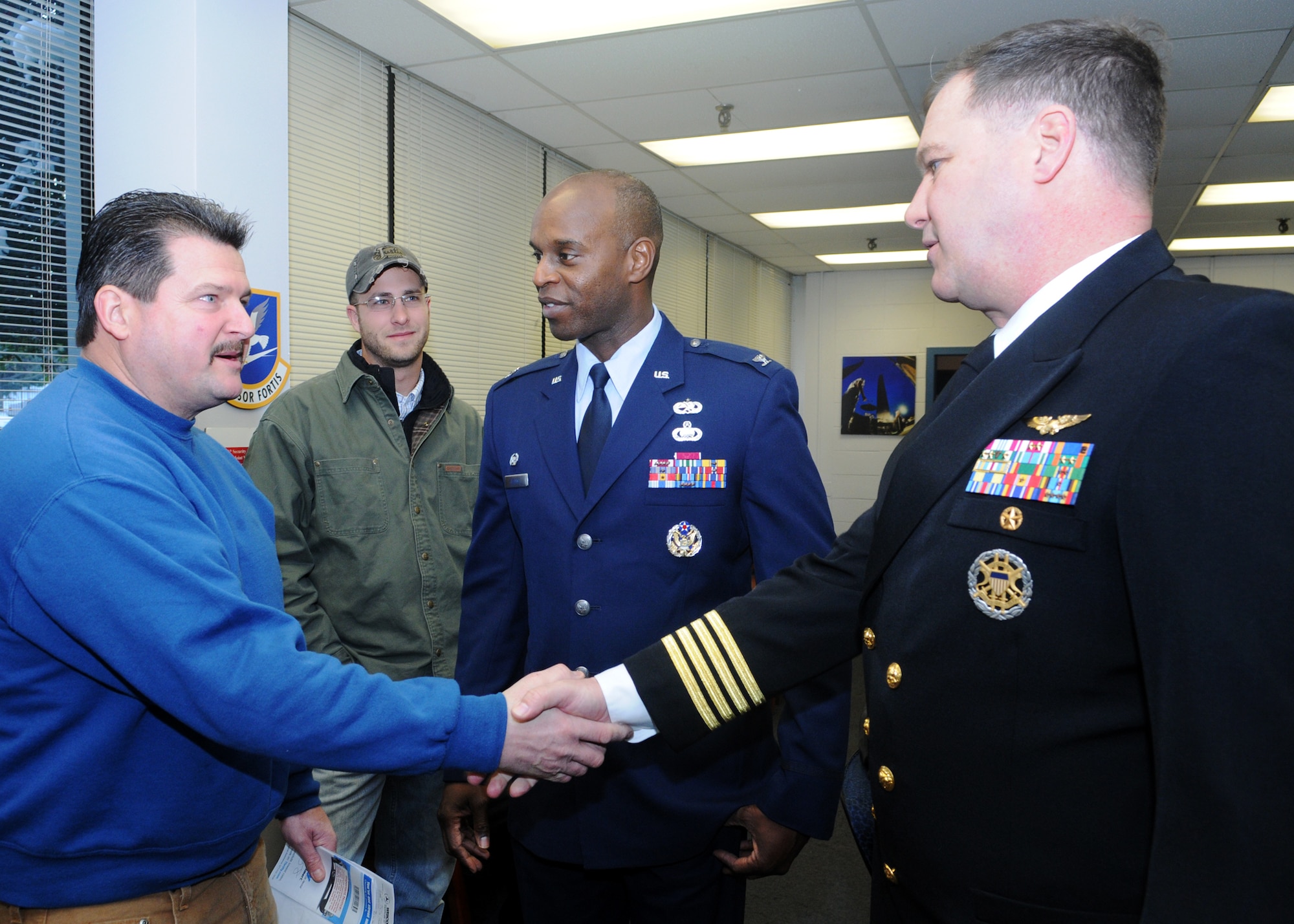 To symbolize the start of the implementation process for joint basing, Navy Capt. John Sears, Naval Support Washington commanding officer, shakes hands with Bob Burkel, Burkel Construction, at the Joint Visitors’ Center at Bolling Air Force Base Feb. 1. Captain Sears and Col. Cedric George, 11th Wing commander, joined forces to welcome folks to the base as a symbolic gesture during the momentous occasion.  The implementation process will continue through Oct. 1, 2010, at which time the joint team will declare the base fully operational.  The implementation process is significant as the Air Force and Navy begin merging service unique functions.  On Oct. 1, 2010, the base will be named Joint Base Anacostia-Bolling, combining Naval Support Facility Anacostia and Bolling Air Force Base. The JVC staff services about 400 people a day and more than 6,000 a month issuing contractor identification, Geneva Convention cards, restricted area badges, visitor passes and vehicle decal registrations.   The staff is comprised of 17 people representing military, civilian, Navy and Air Force. (U.S. Air Force photo by Thomas Dennis)