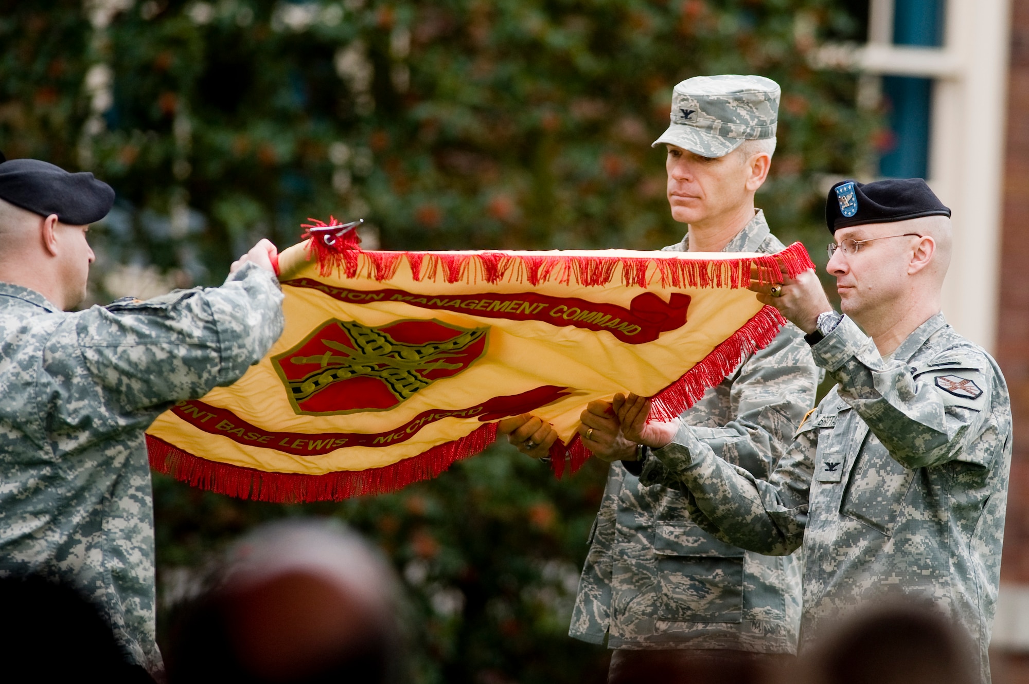 Army Col. Thomas H. Brittain, Joint Base Lewis-McChord commander and Air Force Col. Kenny Weldon, JBLM deputy commander, uncase the JBLM colors during the Initial Operational Capability ceremony in front of JBLM Headquarters Monday. (U.S. Air Force Photo/Abner Guzman)