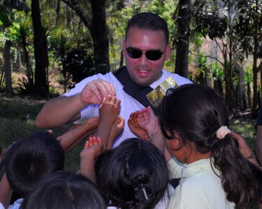 Staff Sgt. Israel Delvalle, 612th Air Base Squadron, passes out candy to the children of Cinacla, Honduras during a Chapel Hike Jan. 23. More than 70 Team Soto Cano members carried more than a ton of food and supplies nearly four miles to the remote community of 300. (U.S. Air Force Photo/Staff Sgt. Bryan Franks)