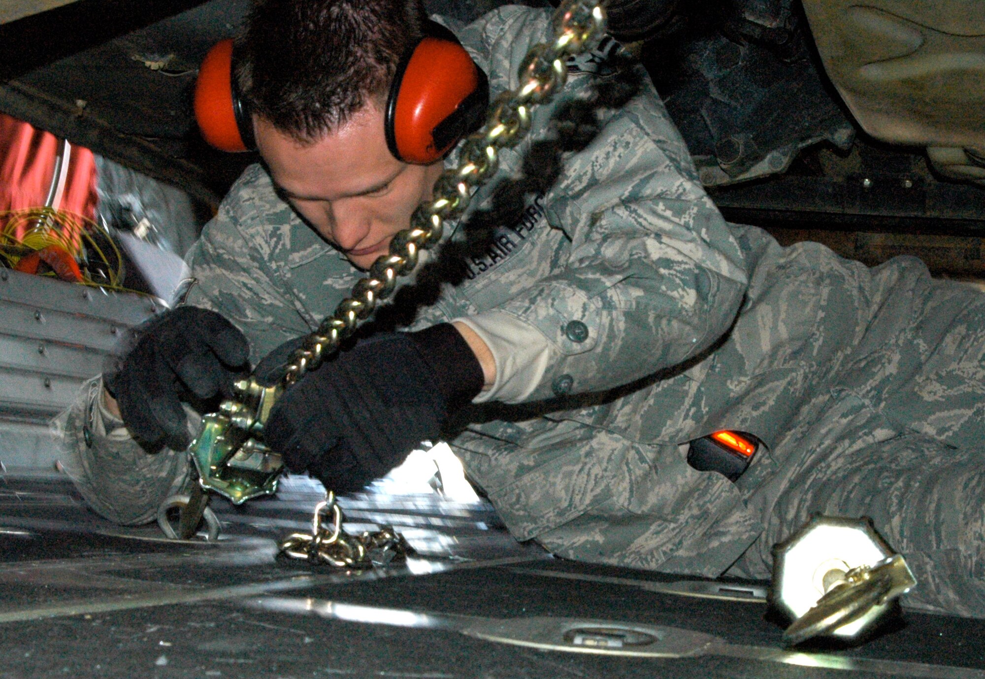 Airman 1st Class Nathan Weiland tightens down the final chain to secure an Army Humvee to a C-130 Hercules Jan. 27, 2010, at Pope Air Force Base, N.C. The Humvee and more than 10 Soldiers assigned to the 82nd Airborne Division were transported by the Minnesota Air National Guard's 133rd Airlift Wing to Haiti where they were expected to fulfill several missions in support of Operation Unified Response, including airport security in the capitol city of Port-au-Prince. Airman Weiland is a cargo rigger with the 3rd Aerial Port Squadron. (U.S. Air Force photo/Staff Sgt. Stephen J. Collier)