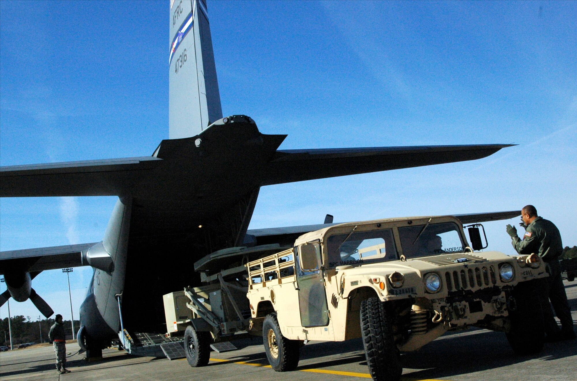 Chief Master Sgt. Byron Todd (far right) guides Army Staff Sgt. Luke Skinner as he backs a satellite communication uplink trailer into an awaiting Air Force Reserve C-130 Hercules Jan. 27, 2010, at Pope Air Force Base, N.C. Sergeant Skinner and more than 10 members of his unit later arrived at Port-au-Prince, Haiti, where they deployed in support of earthquake relief operations. Chief Todd is a loadmaster assigned to the Minnesota Air National Guard's 133rd Airlift Wing in Minneapolis-St. Paul. Both the C-130 and its aircrew are deployed to Muniz Air Base, Puerto Rico, in support of Coronet Oak. Sergeant Skinner is assigned to the 82nd Airborne Division. (U.S. Air Force photo/Staff Sgt. Stephen J. Collier)