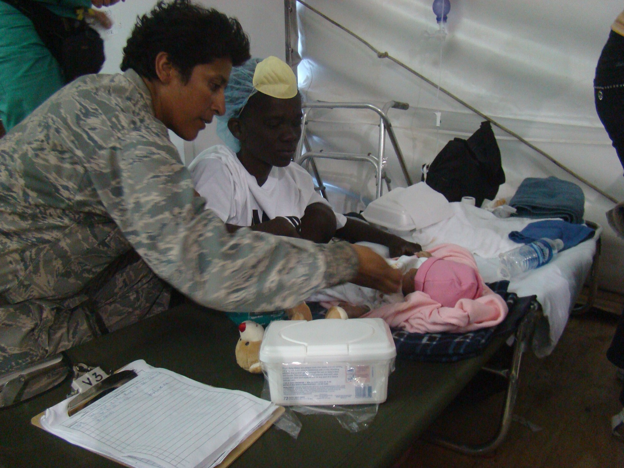 Chaplain (Capt.) Eusebia D. Rios blesses one of three triplets in the children's ward of the University of Miami Hospital compound adjacent to the Toussaint L'Ouverture International Airport in Port au Prince, Haiti, Jan. 29, 2010. The babies were born in the wake of the 7.1 magnitude earthquake which devastated the capital city Jan.12, 2010. Chaplain Rios, deployed from the 27th Special Operations Wing at Cannon Air Force Base, N.M. serves as the only chaplain to more than 1,500 military men and women encamped at the airport as part of Operation Unified Response. Known as the "Happy Chappy," Chaplain Rios ranges the airport day and night ministering to the needs of military and civilian alike, lifting their spirits and raising morale with each "Amen" she offers. (U.S. Air Force photo by Chief Master Sgt. Ty Foster)              