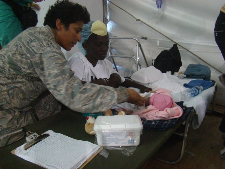Chaplain (Capt.) Eusebia D. Rios blesses one of three triplets in the children's ward of the University of Miami Hospital compound adjacent to the Toussaint L'Ouverture International Airport in Port au Prince, Haiti, Jan. 29, 2010. The babies were born in the wake of the 7.1 magnitude earthquake which devastated the capital city Jan.12, 2010. Chaplain Rios, deployed from the 27th Special Operations Wing at Cannon Air Force Base, N.M. serves as the only chaplain to more than 1,500 military men and women encamped at the airport as part of Operation Unified Response. Known as the "Happy Chappy," Chaplain Rios ranges the airport day and night ministering to the needs of military and civilian alike, lifting their spirits and raising morale with each "Amen" she offers. (U.S. Air Force photo by Chief Master Sgt. Ty Foster)              