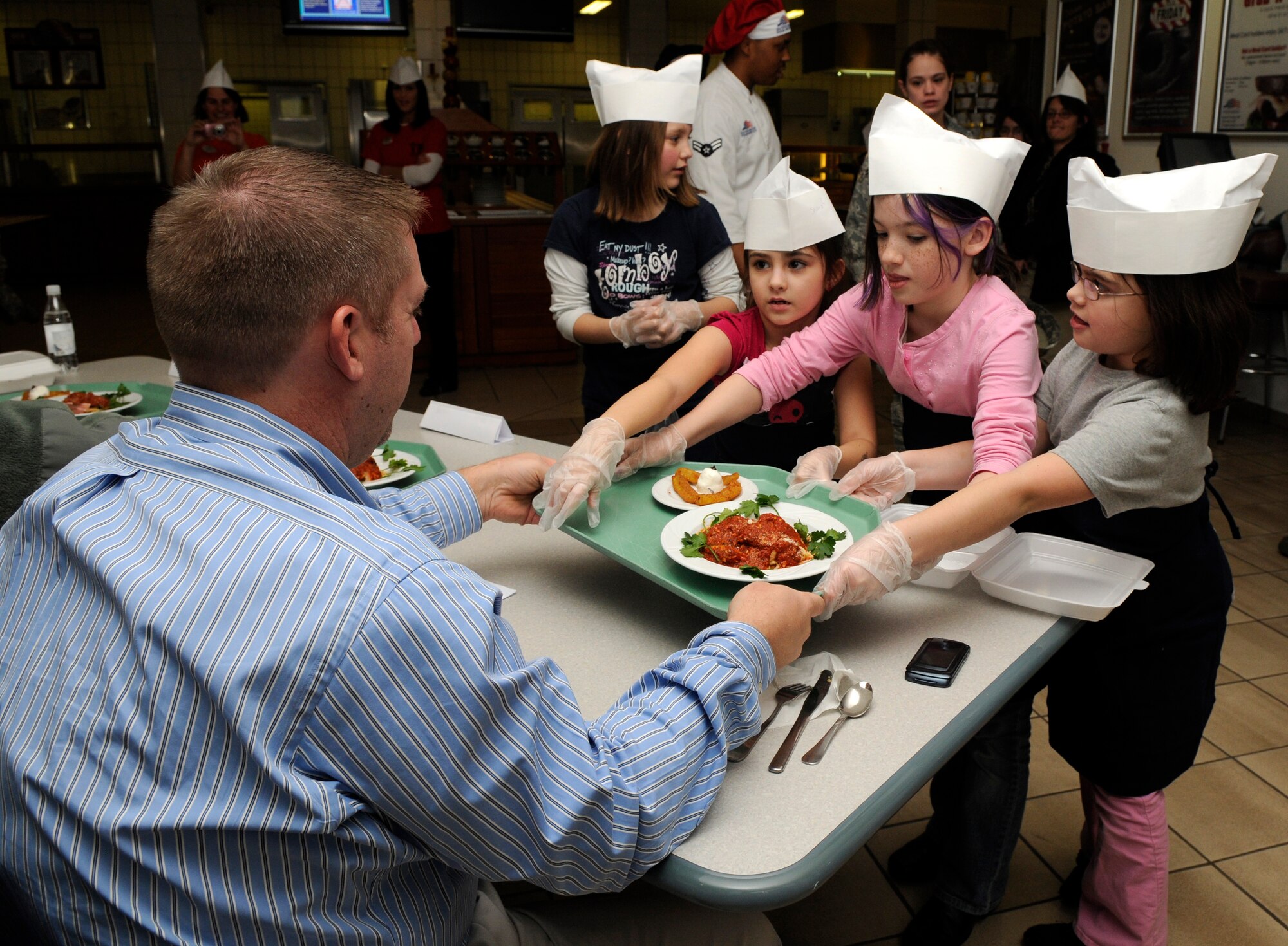 SPANGDAHLEM AIR BASE, Germany – Team Two delivers their dish to the judge table for evaluation during the Kid’s Iron Chef Competition at the Mosel Dining Facility Jan. 27. Students from the Spangdahlem Middle School were split into three teams, and each team created a different dish to be judged. Team Three took first place with their sweet chicken curry dish.  (U.S. Air Force photo/Airman 1st Class Staci Miller)