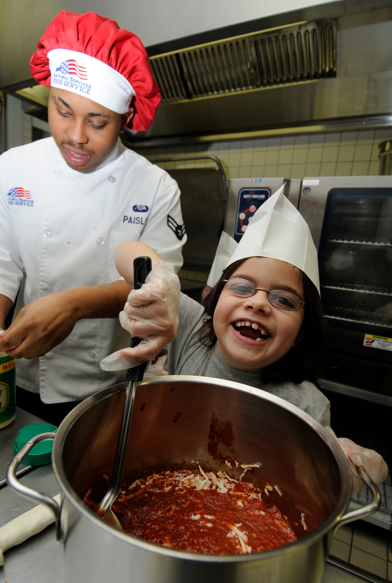 SPANGDAHLEM AIR BASE, Germany – Katie Smith, daughter of Amy Smith, 52nd Force Support Squadron, helps Team Two create a dish during the Kid’s Iron Chef Competition at the Mosel Dining Facility Jan. 27. Students from the Spangdahlem Middle School were split into three teams, and each team created a different dish to be judged.  (U.S. Air Force photo/Airman 1st Class Staci Miller)
