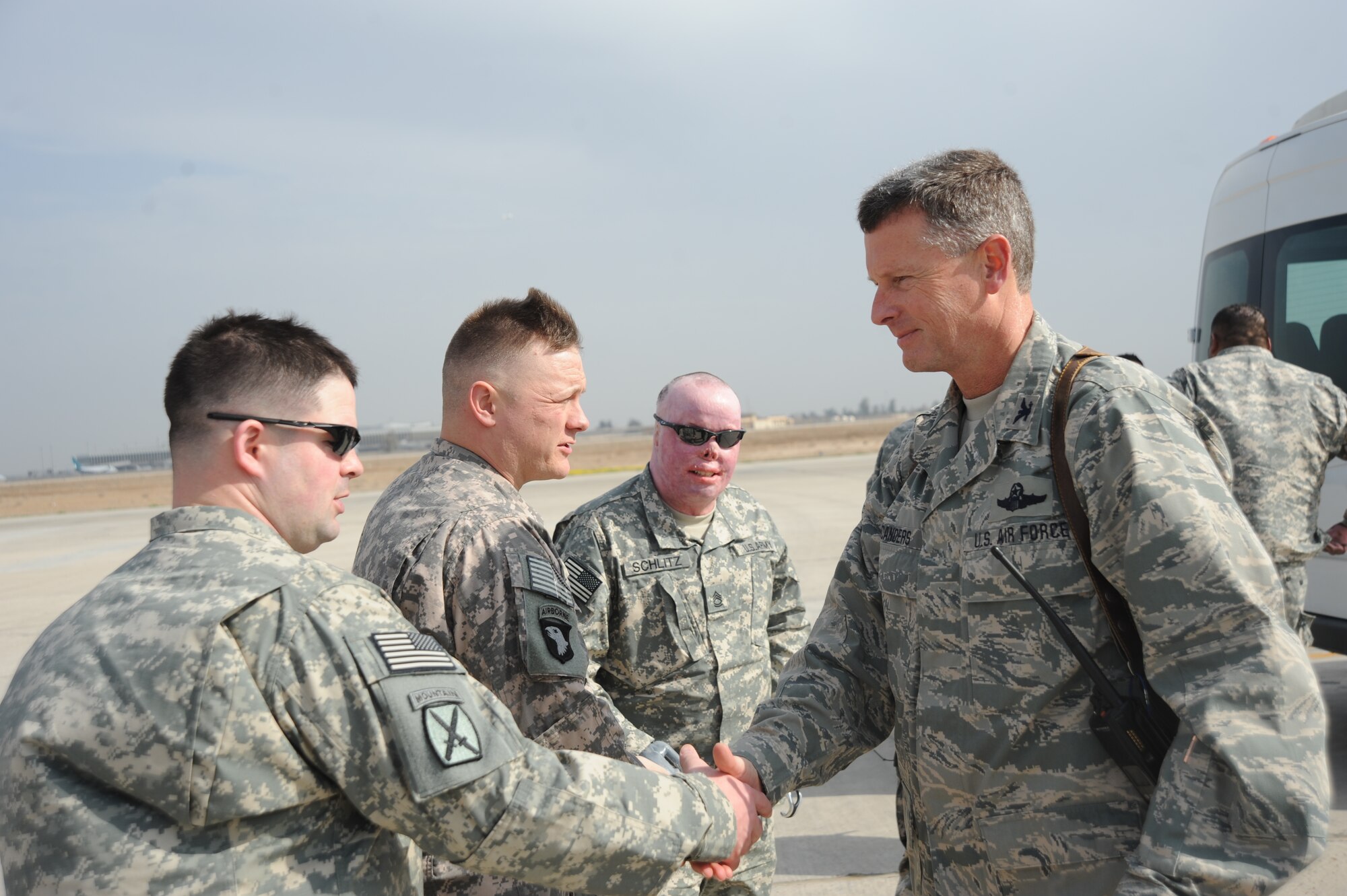 Col. Michael Canders, 447th Air Expeditionary Group commander coins members of Opertation Proper Exit as they start their tour around Victory Base Complex Jan.31, 2010. Operation Proper Exit is a program where service members who have been injured in Iraq revisit to help bring emotional closure. 