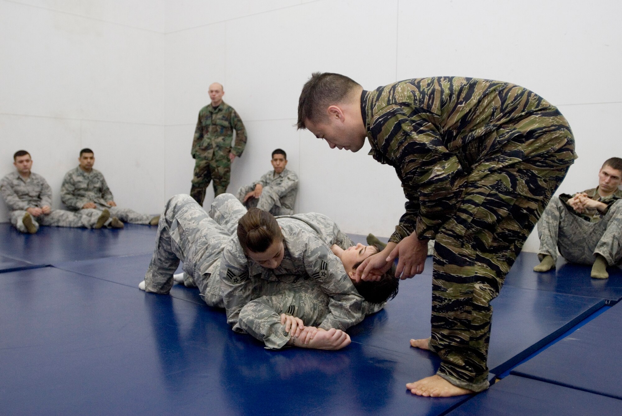 KUNSAN AIR BASE, Republic of Korea -- Senior Airman Casaundra Soto performs an arm bar on Senior Airman Heather Bell, both from the 8th Security Forces Squadron, while Staff Sgt. Tony Fancher, 8th Operations Support Squadron survival evasion resistance and escape specialist, coaches her through the moves during combatives training Jan. 27. The SFS members complete 10 hours of combatives training based off the Army's Modern Army Combatives Program which focuses on basic ground fighting techniques. (U.S. Air Force photo/Senior Airman Jonathan Steffen)
